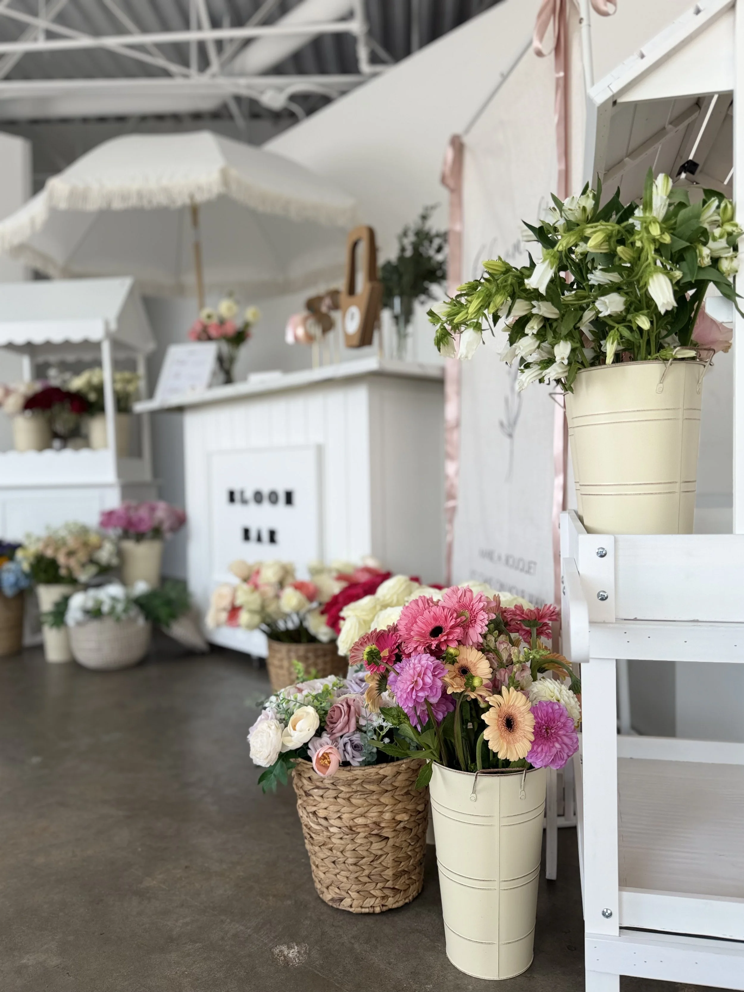 White bloom bar cart with parasol and greenery at an outdoor Colorado event