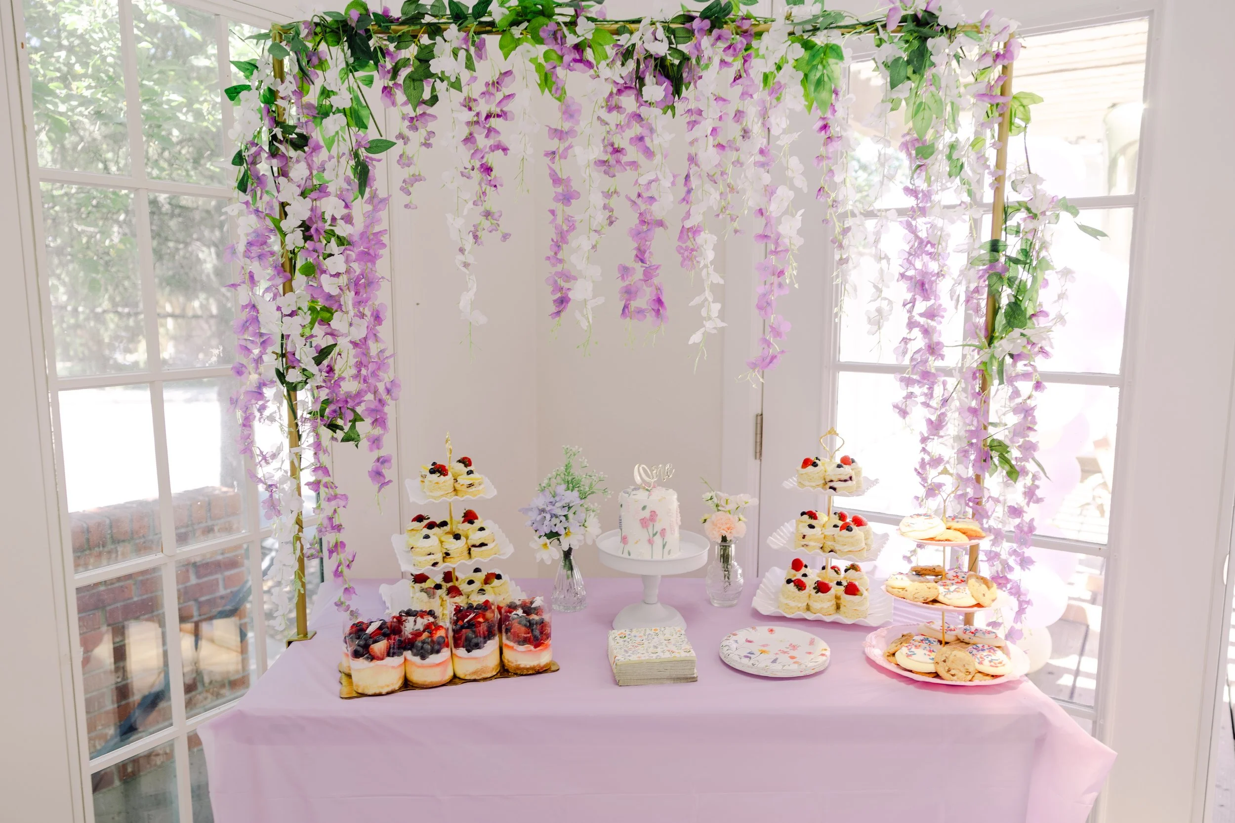 Purple wisteria canopy over a dessert table at a Colorado event