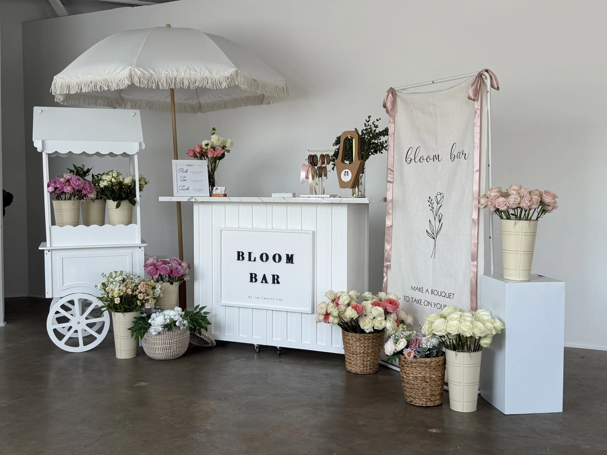 Indoor white bloom bar cart with parasol, blooms, and woven baskets in Colorado