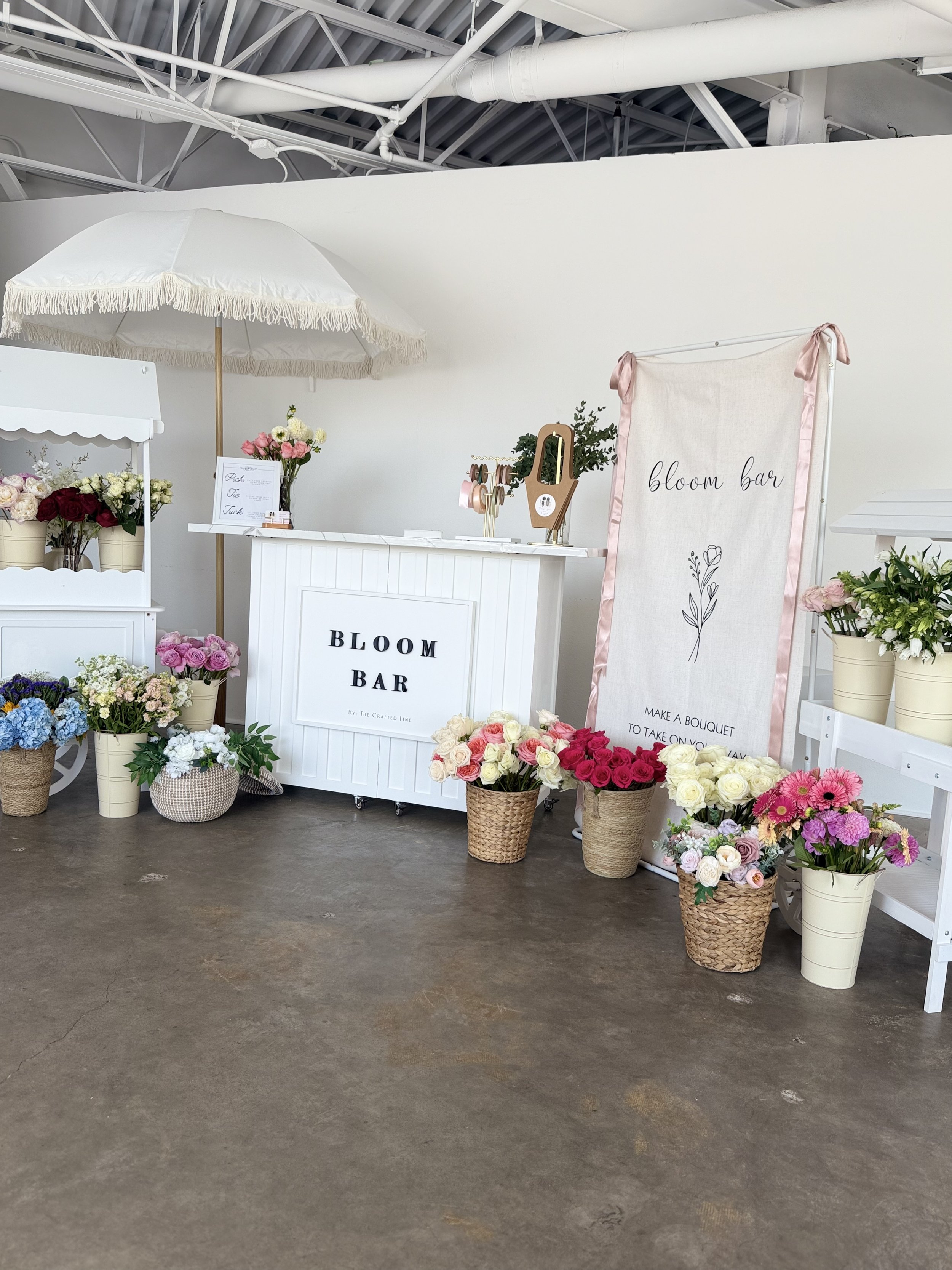 White bloom bar cart with parasol and signage at a Colorado market