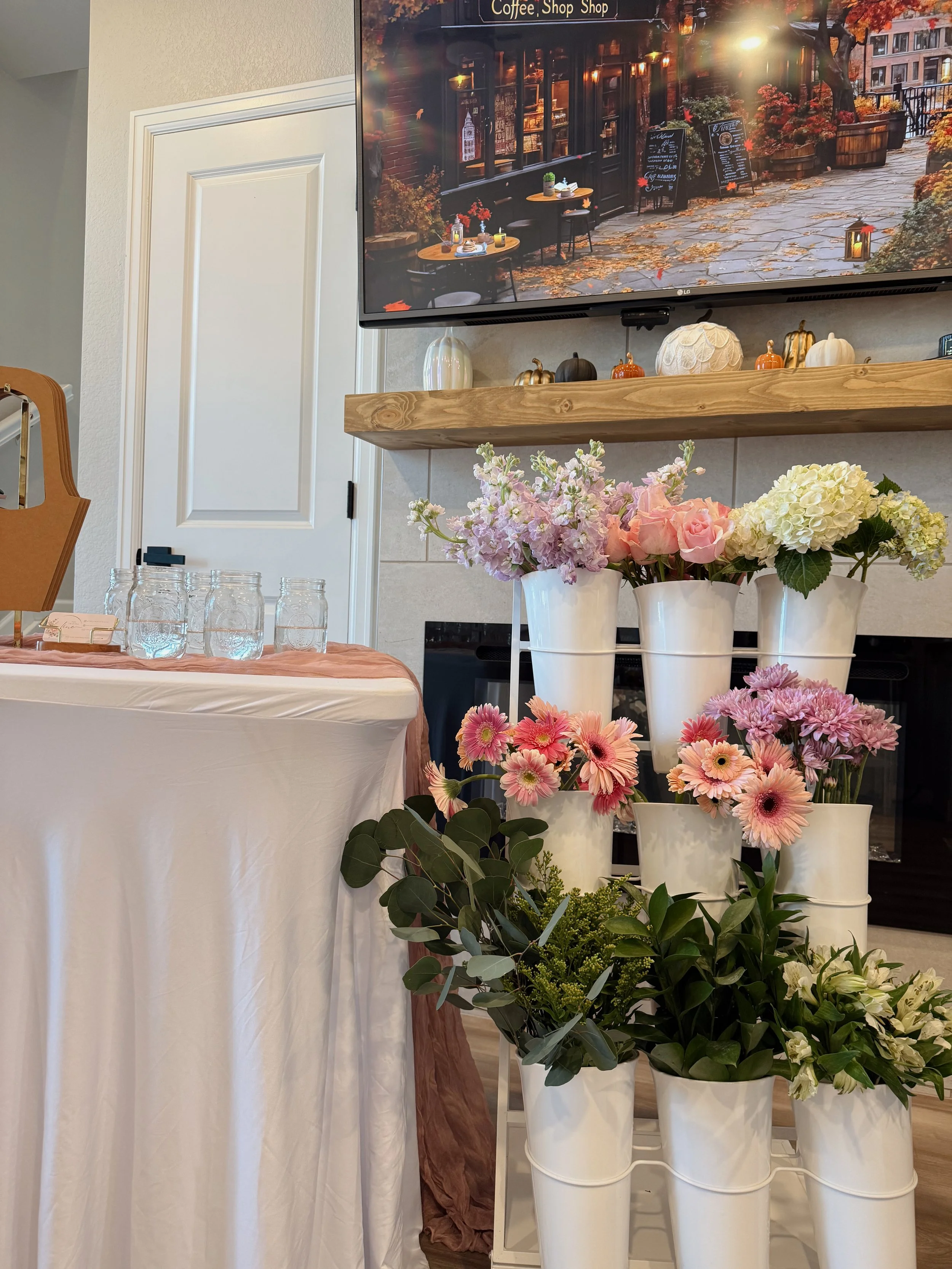 A bright outdoor bloom bar with a white wooden counter and colorful florals ready for bouquet‑making. Designed for weddings, showers, and guest‑interactive experiences.