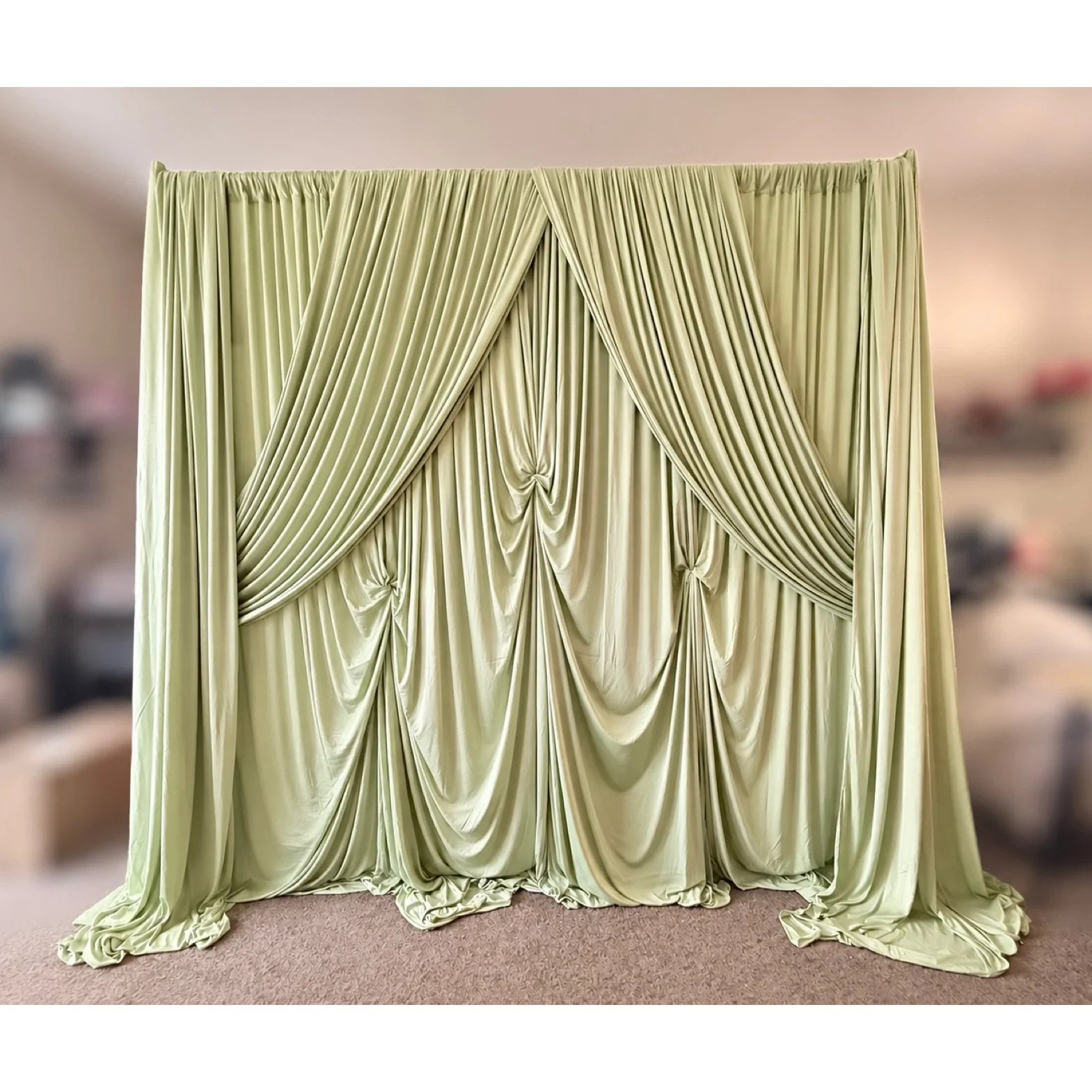 Sophisticated sage‑green backdrop draping with cascading layers and a polished, symmetrical design ideal for modern celebrations. The rich texture and structured swags elevate event spaces, making it a stunning rental option for weddings, engagement 