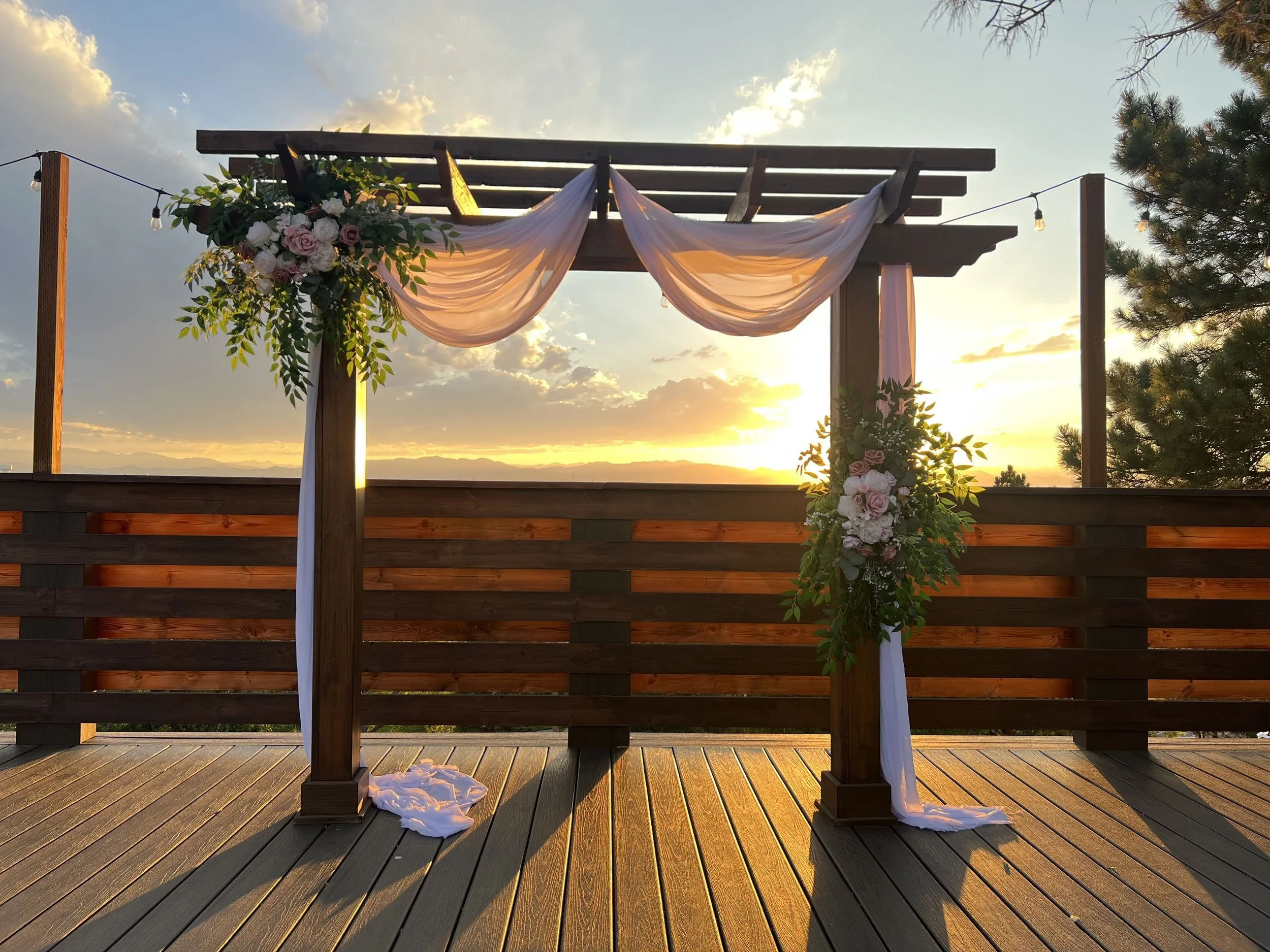 A wooden ceremony deck overlooking a natural landscape, styled with soft florals and draping. Ideal for couples wanting a serene, nature‑inspired setting.