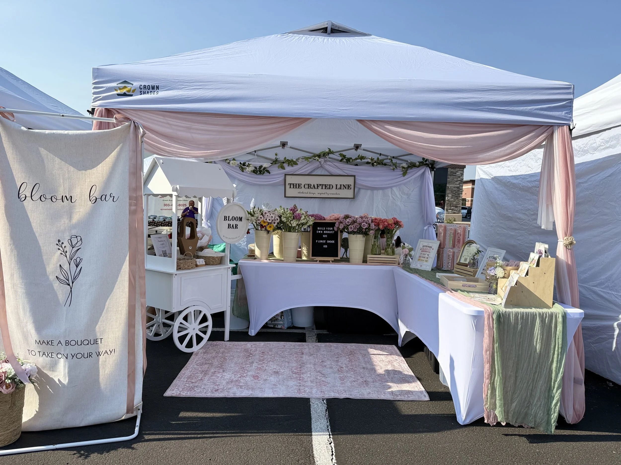 White market tent bloom bar booth with florals at an outdoor Colorado event