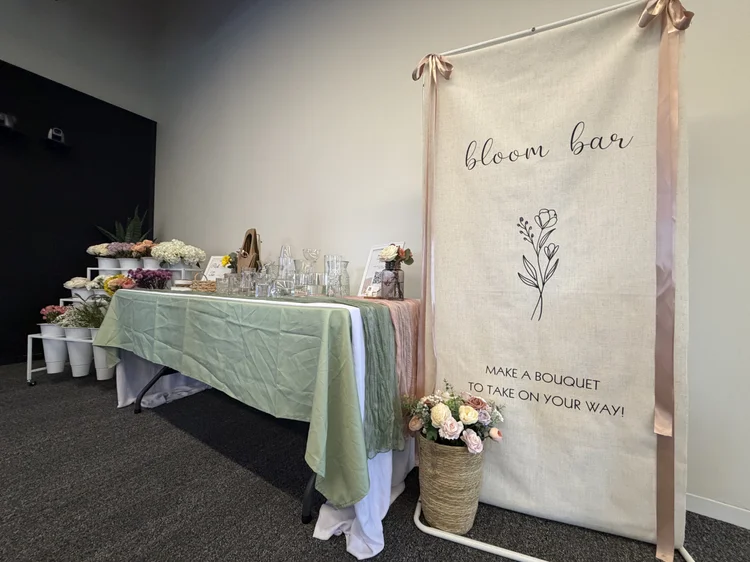 Bloom bar setup with pastel tablecloth and bouquet banner