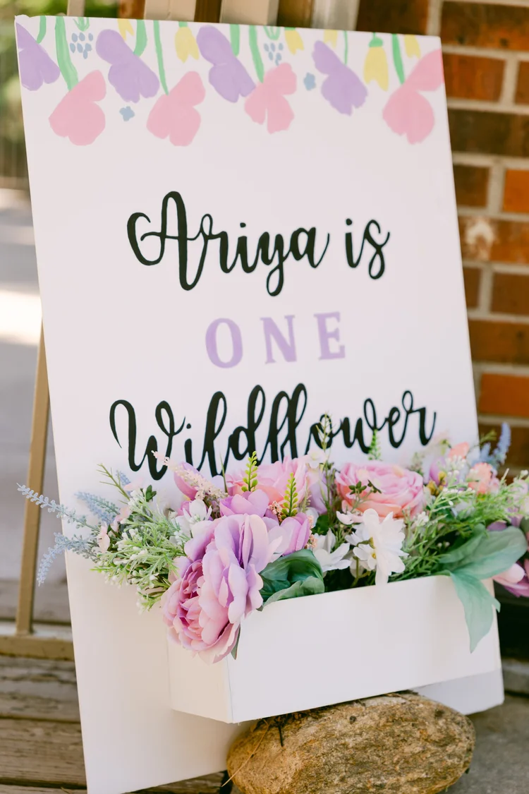 Wildflower first birthday sign decorated with pink purple and white flowers