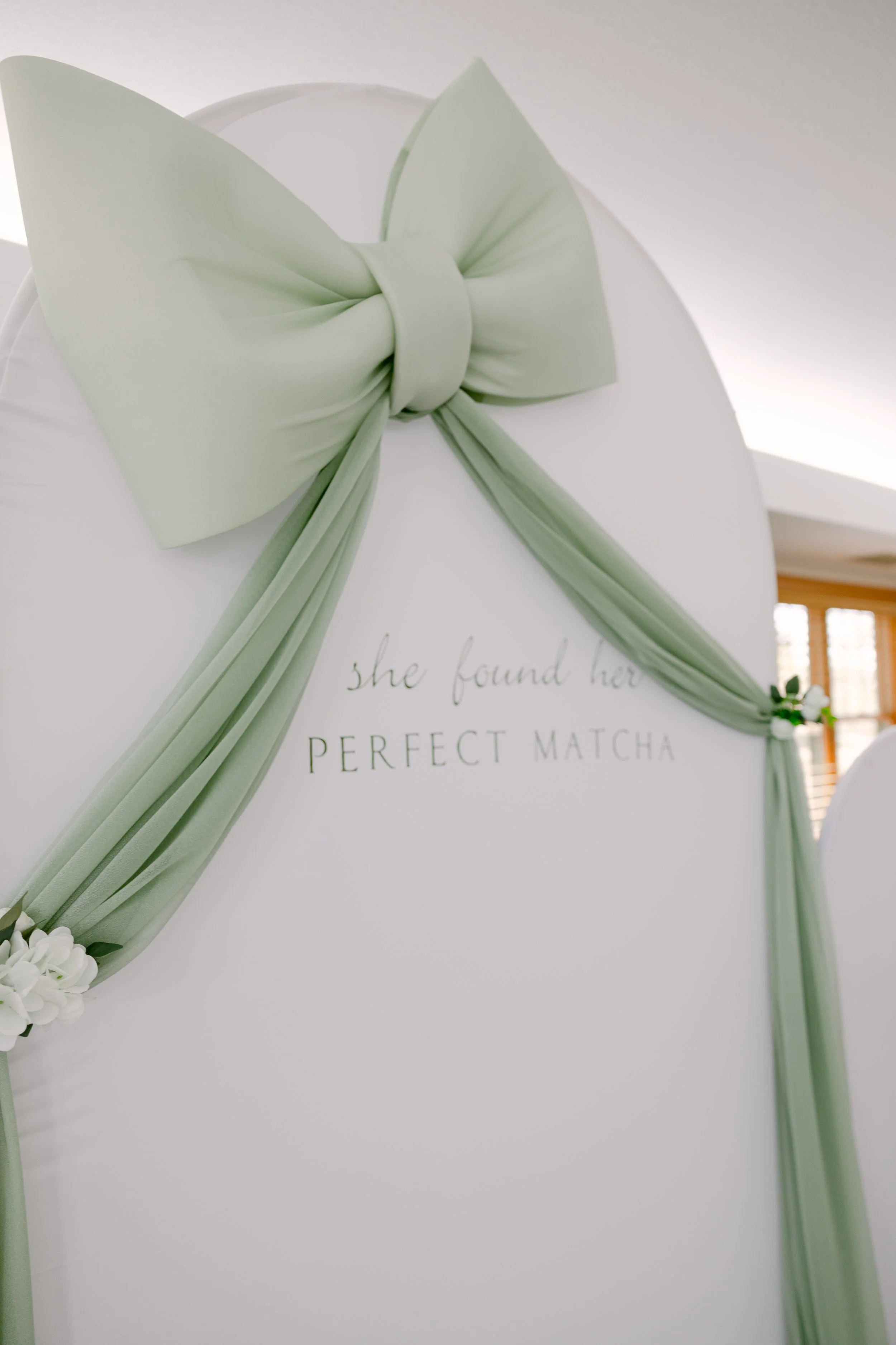 Sage green fabric bow on a white wedding backdrop in Colorado