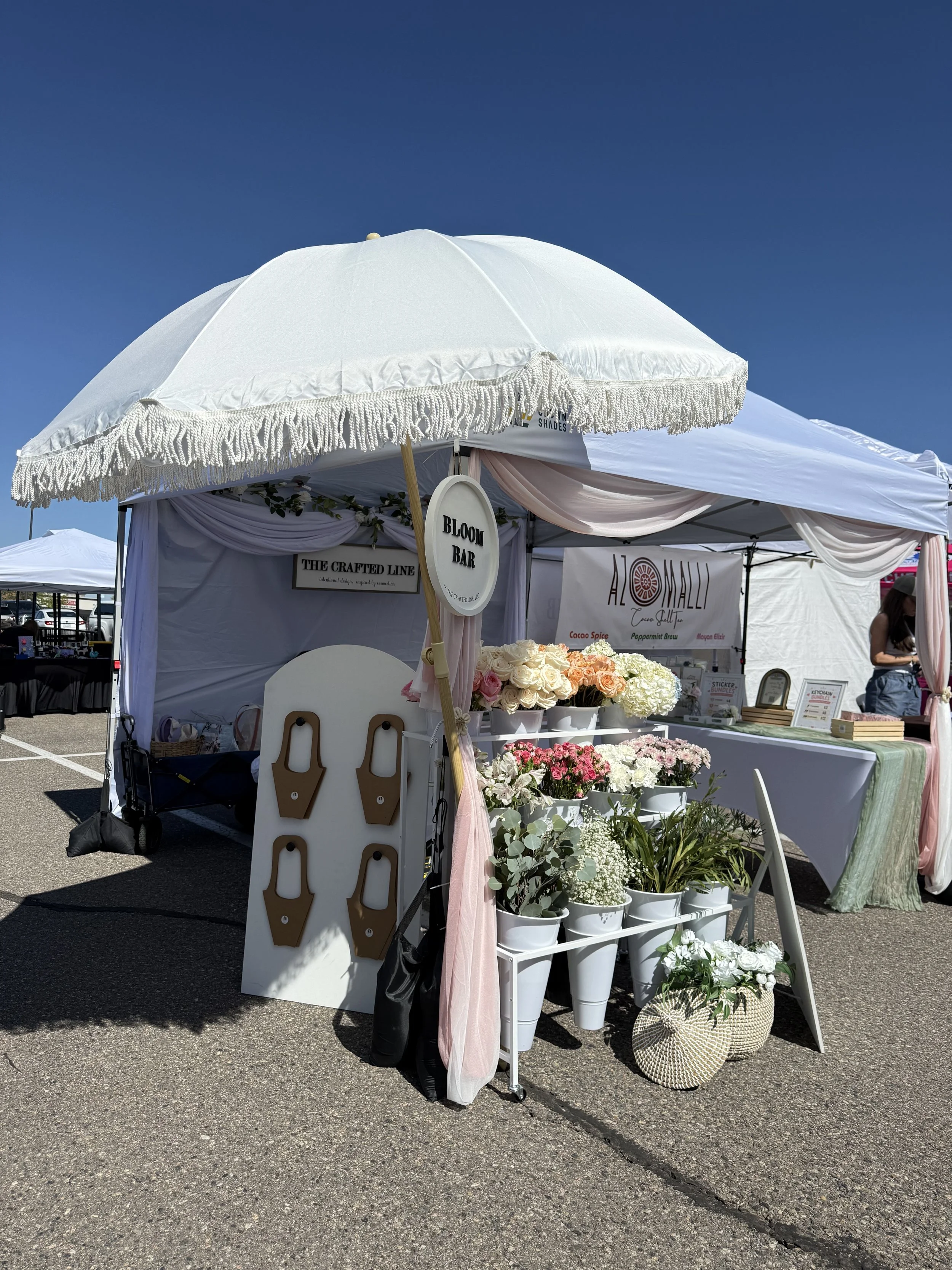 White floral cart with parasol and buckets of blooms at an outdoor Colorado market