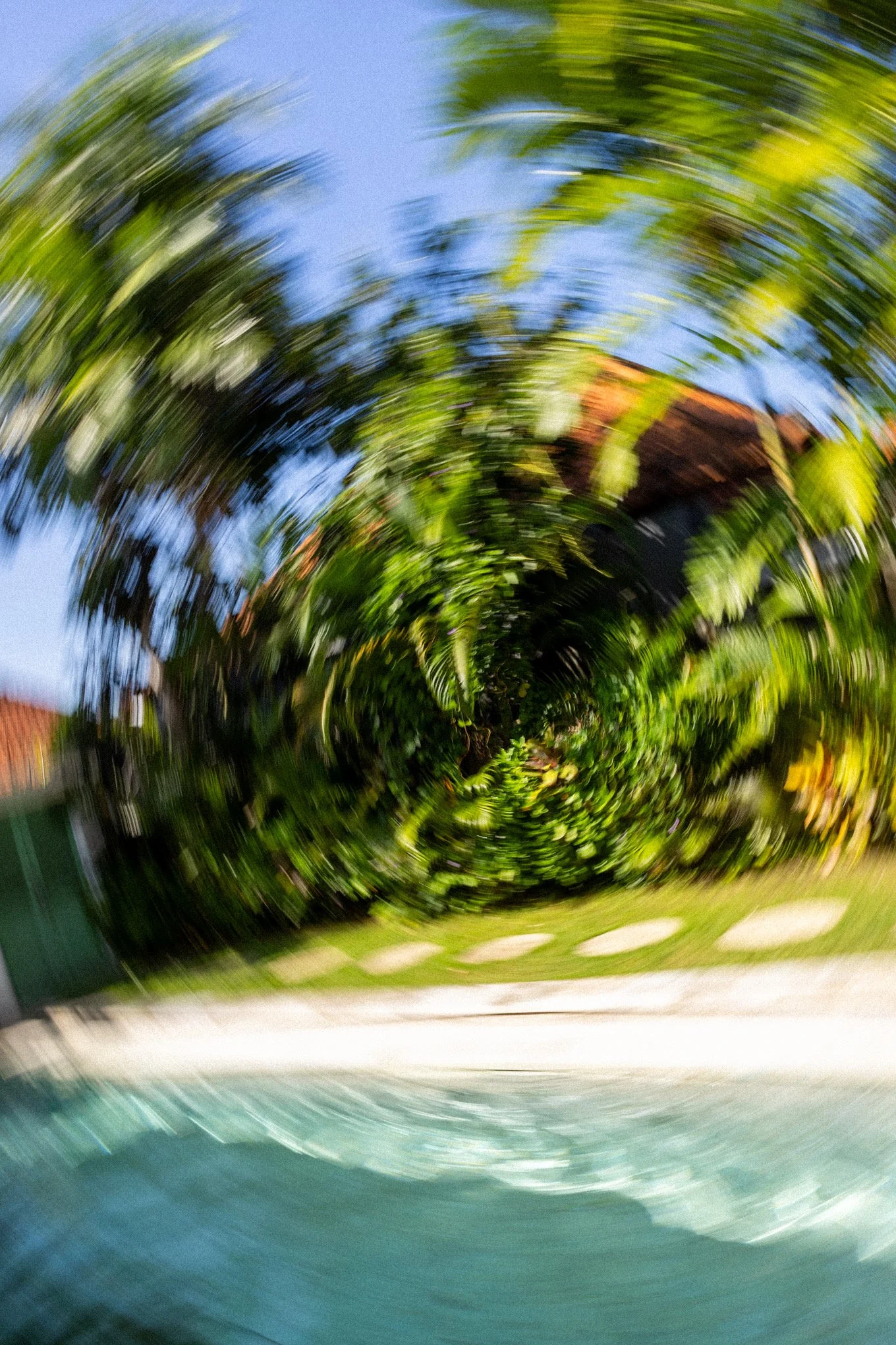 A distorted outdoor scene with trees, blue sky, and a building in the background, with a swirling motion effect.