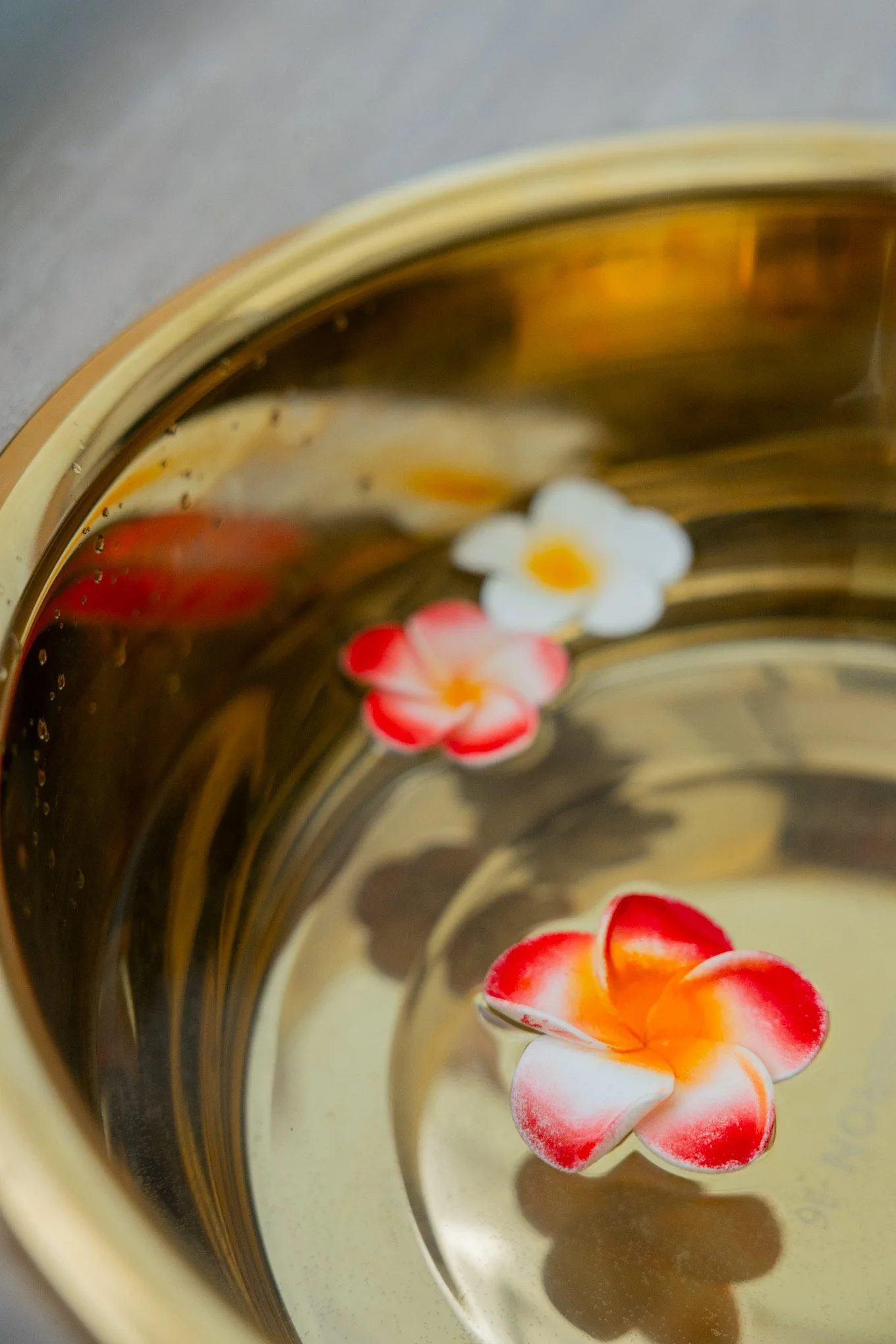 Close-up view of a glass filled with a light-colored beverage, garnished with a white flower and red berries, with a slightly blurred background.