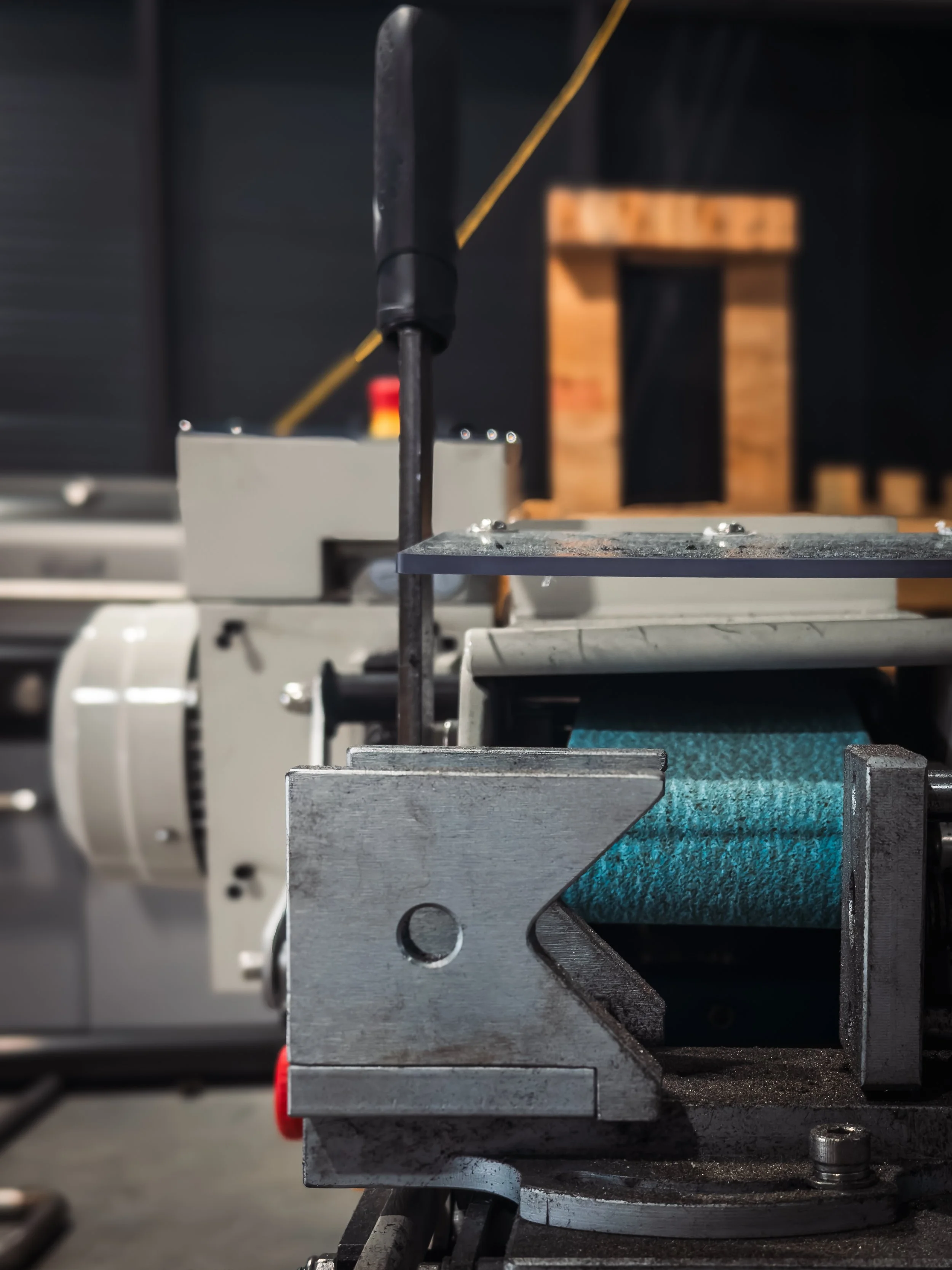 Close-up of a metal machine component with screws and a textured blue pad in an industrial setting.