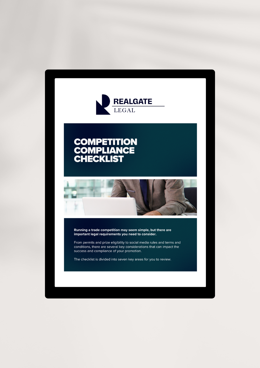 Digital document titled "Competition Compliance Checklist" from RealGATE Legal, with a professional person working on a laptop in the background.