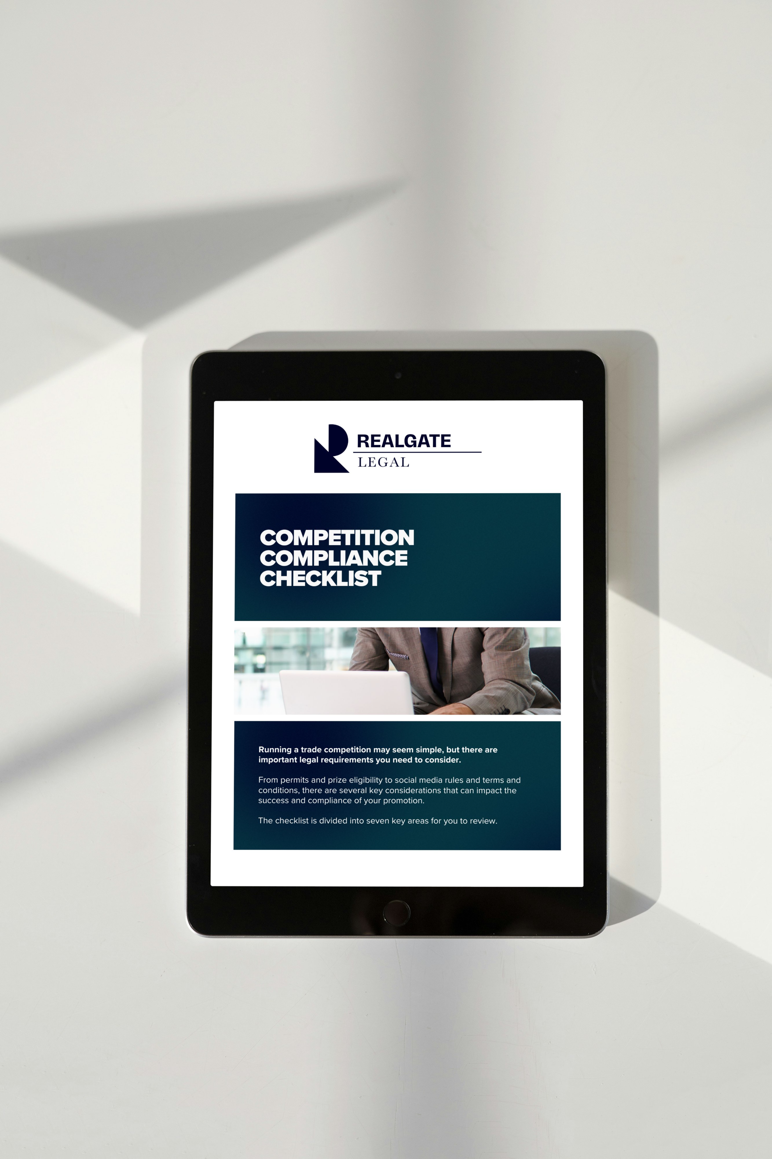 Tablet displaying a legal document titled 'Competition Compliance Checklist' from RealGate Legal, with a professional image of a person in business attire in the background.