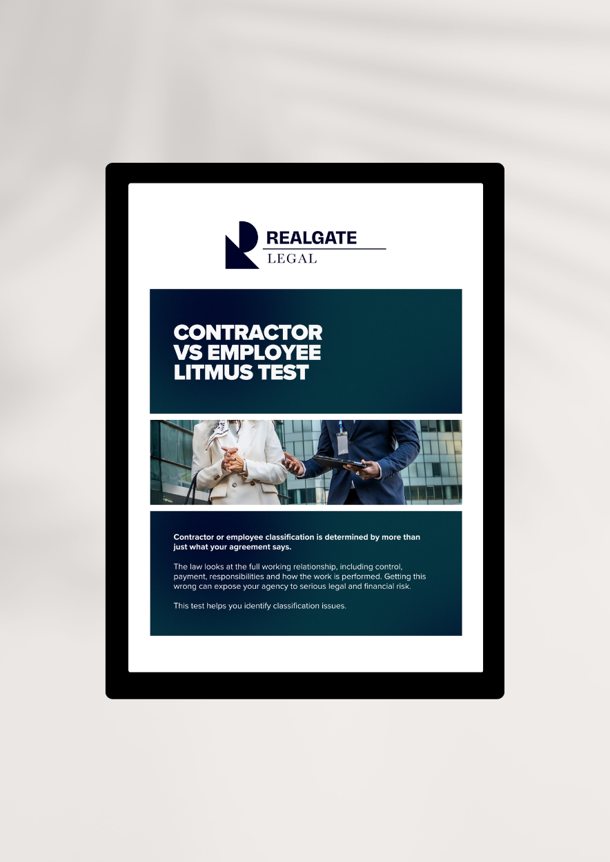A tablet displaying a legal document titled 'Contractor vs Employee Litmus Test' from RealGATE Legal, with an image of two business people shaking hands in an office building.