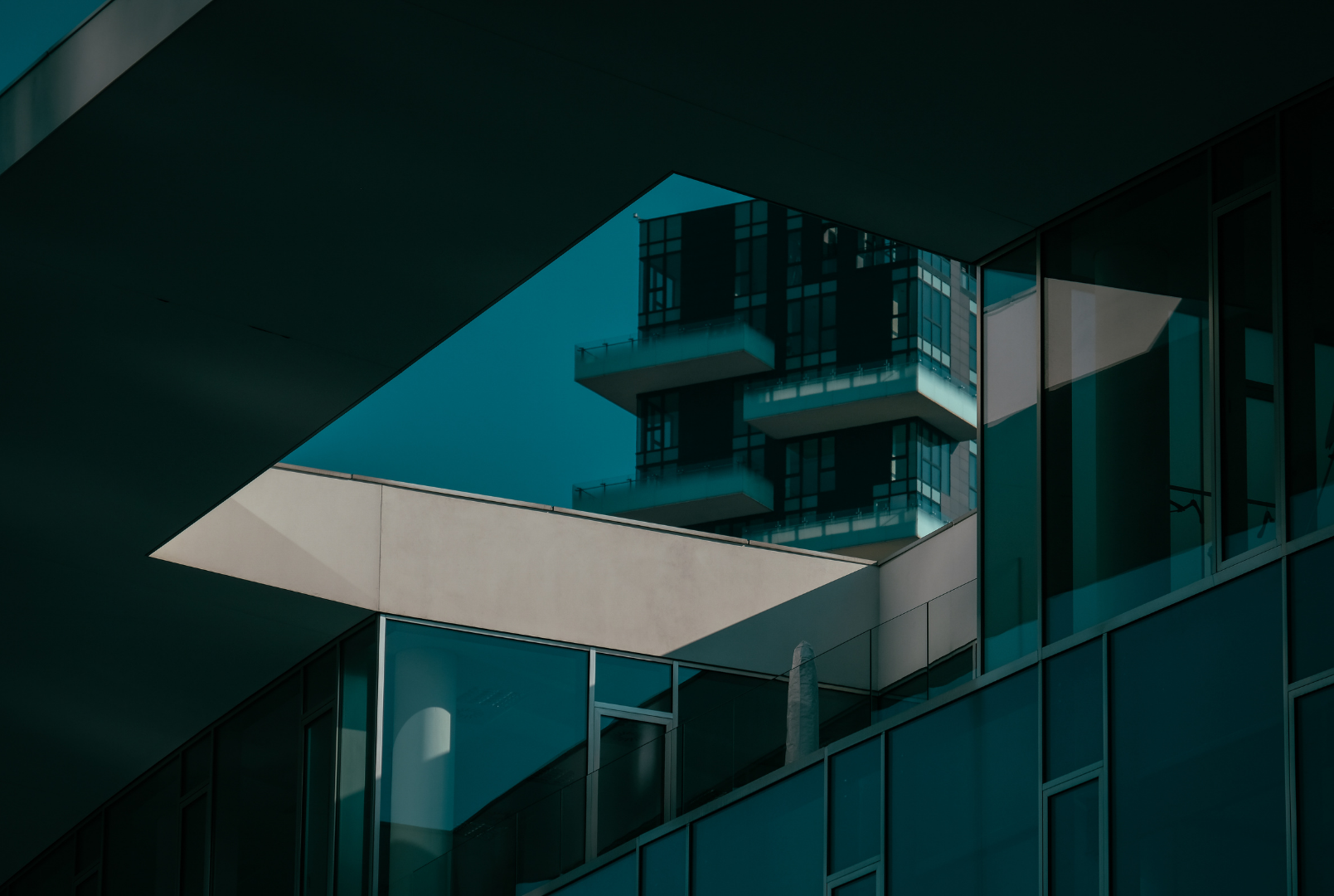 Close-up of modern glass building with reflections, exhibiting architectural shapes and shadows.