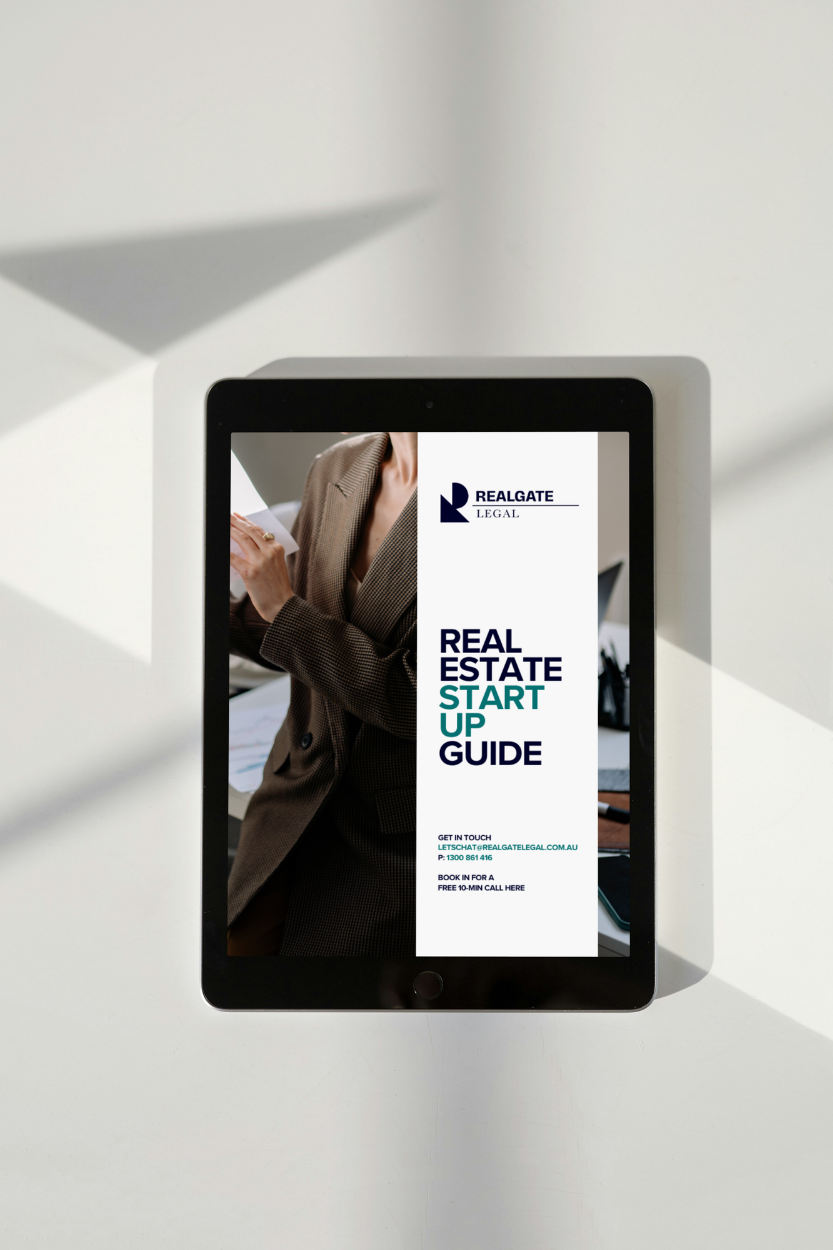 Tablet displaying a real estate startup guide with a woman in business attire on the cover, and contact information for Realgate Legal.