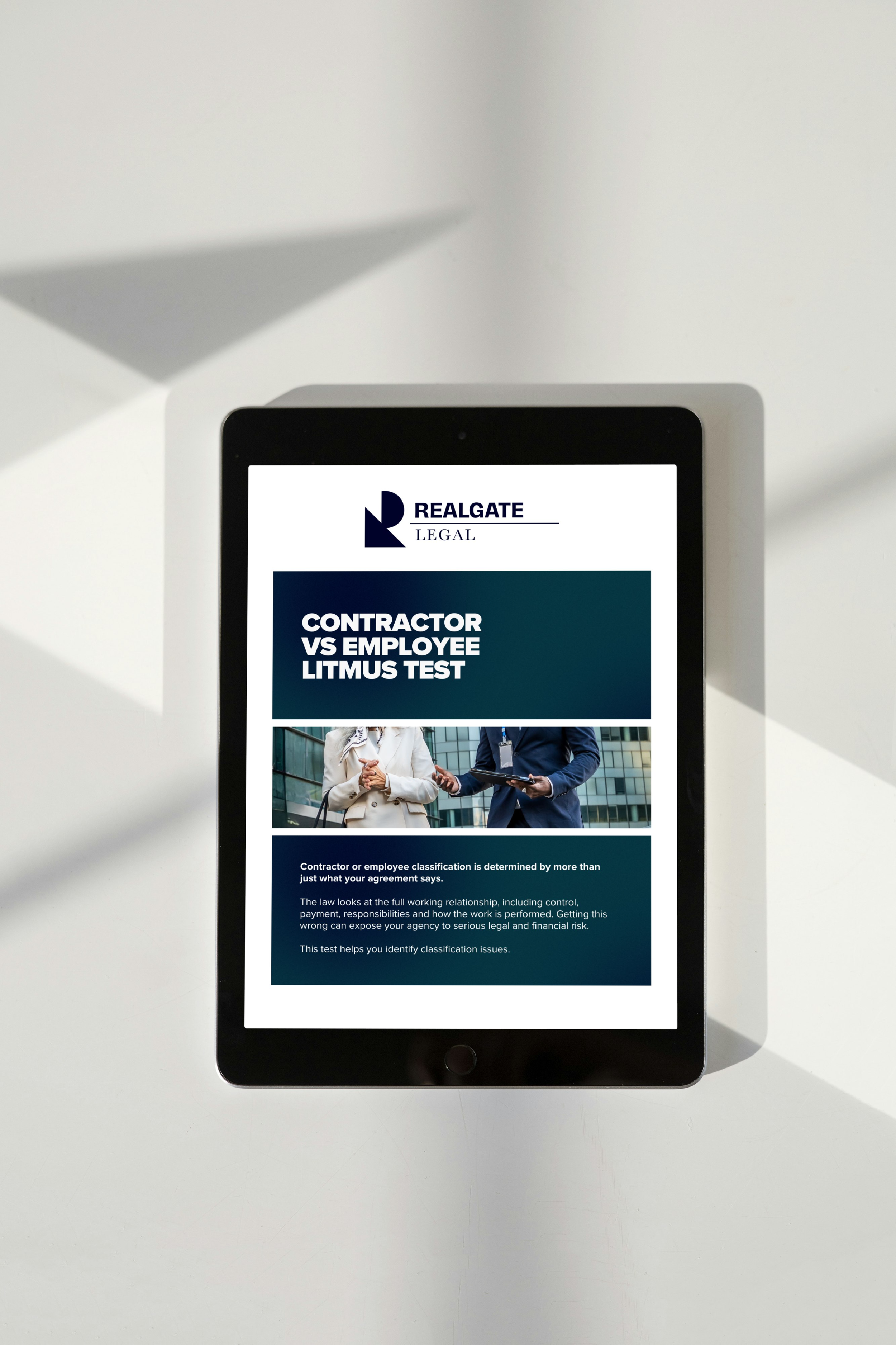 Tablet displaying a legal document titled 'Contractor vs Employee Litmus Test' from RealGATE Legal, showing a photo of two business professionals shaking hands.