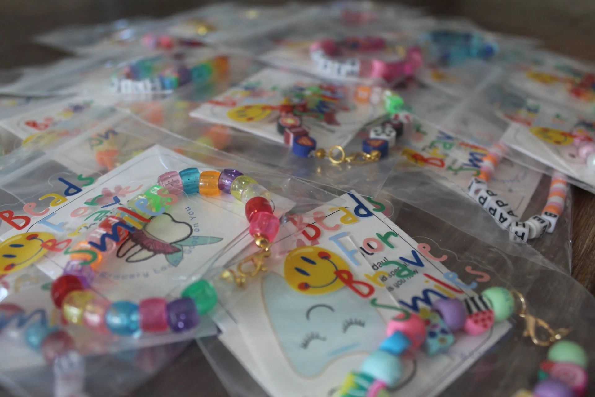 Colorful beaded bracelets with unicorn and rainbow designs, lying on packaged 'Beaded Bracelets' craft kits.