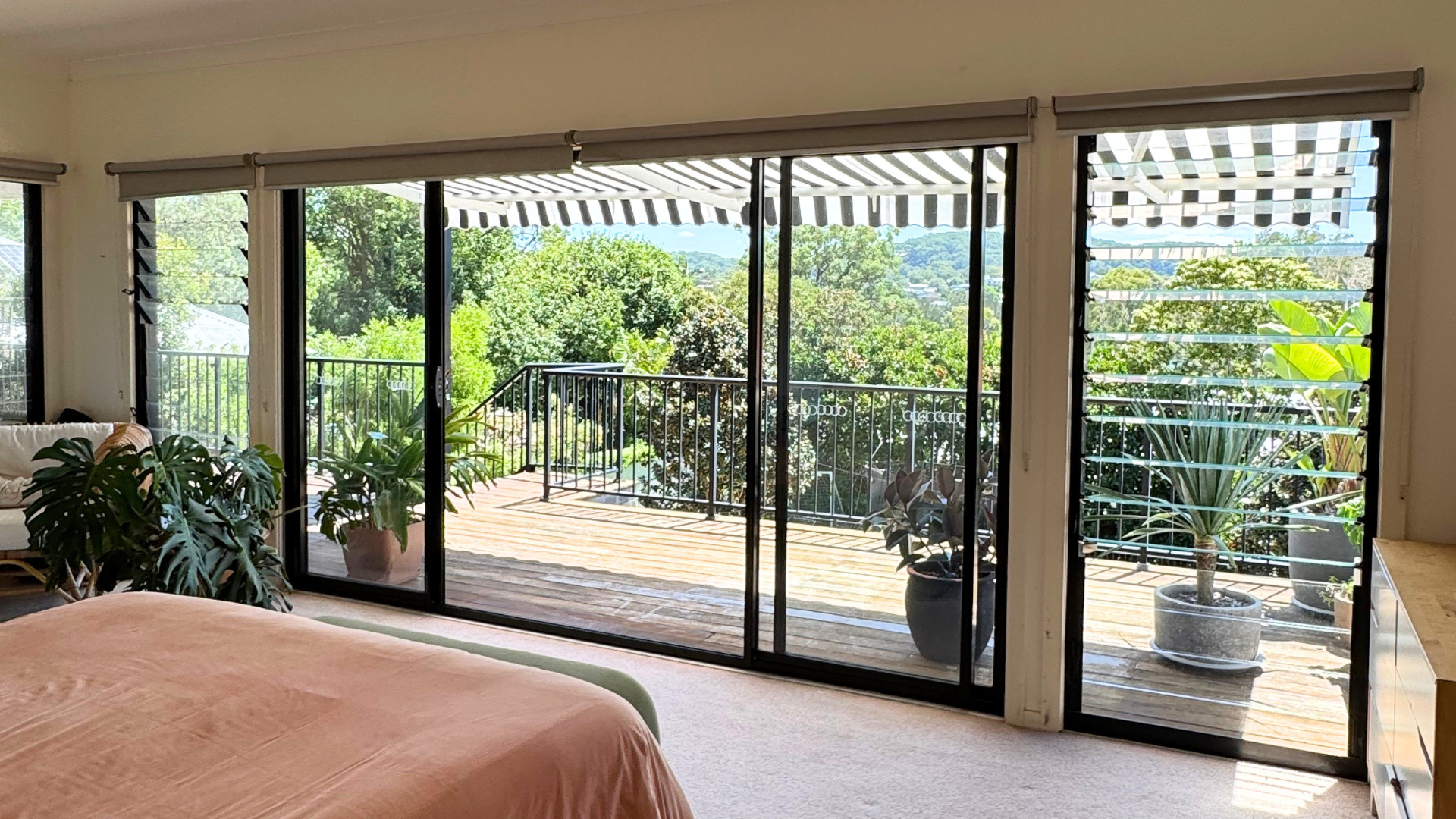 Open-plan living room with sliding doors onto a deck and leafy Central Coast view in an Australian family home.