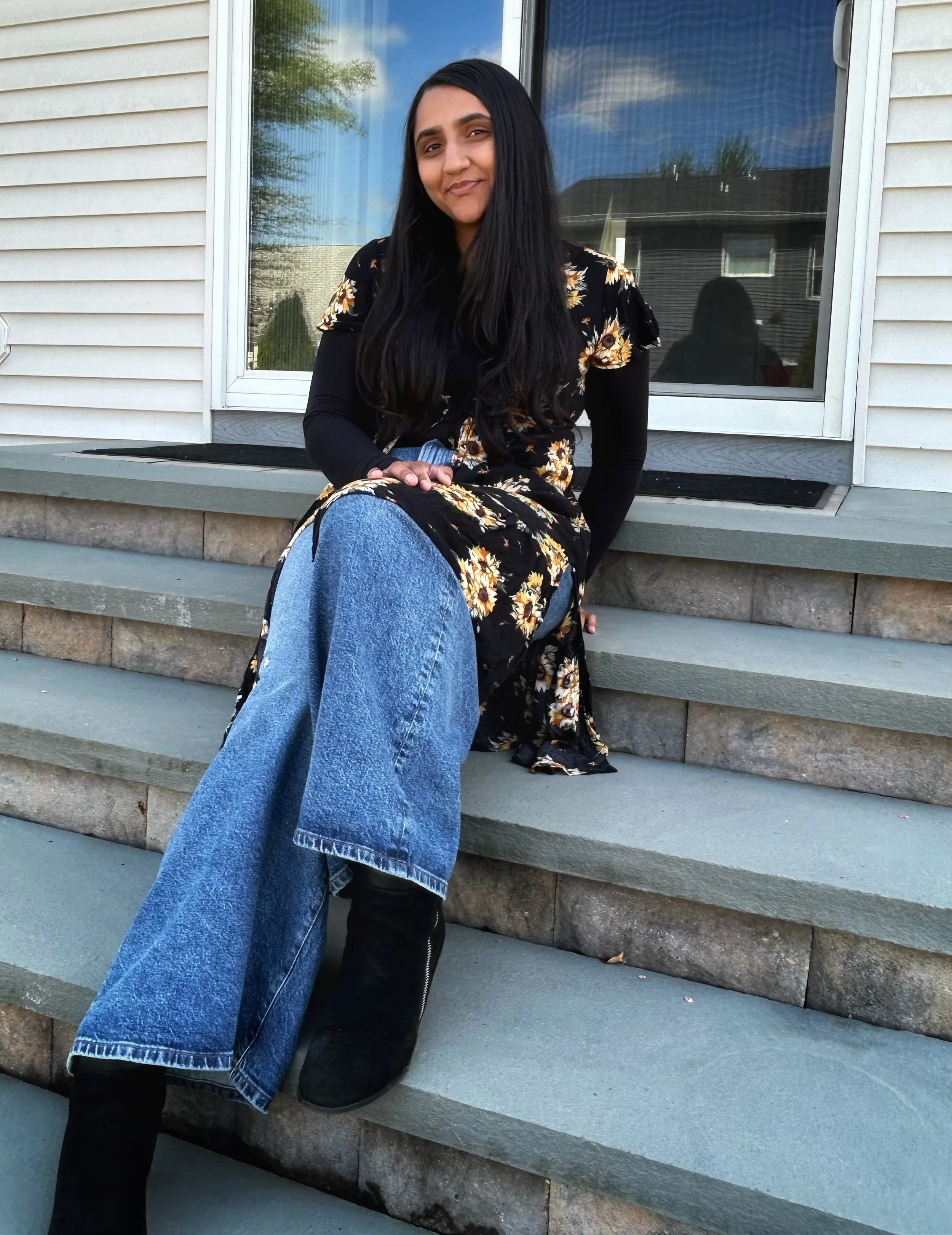 Khushi, founder of Renewed by Love Life Coaching, sitting outdoors and smiling.