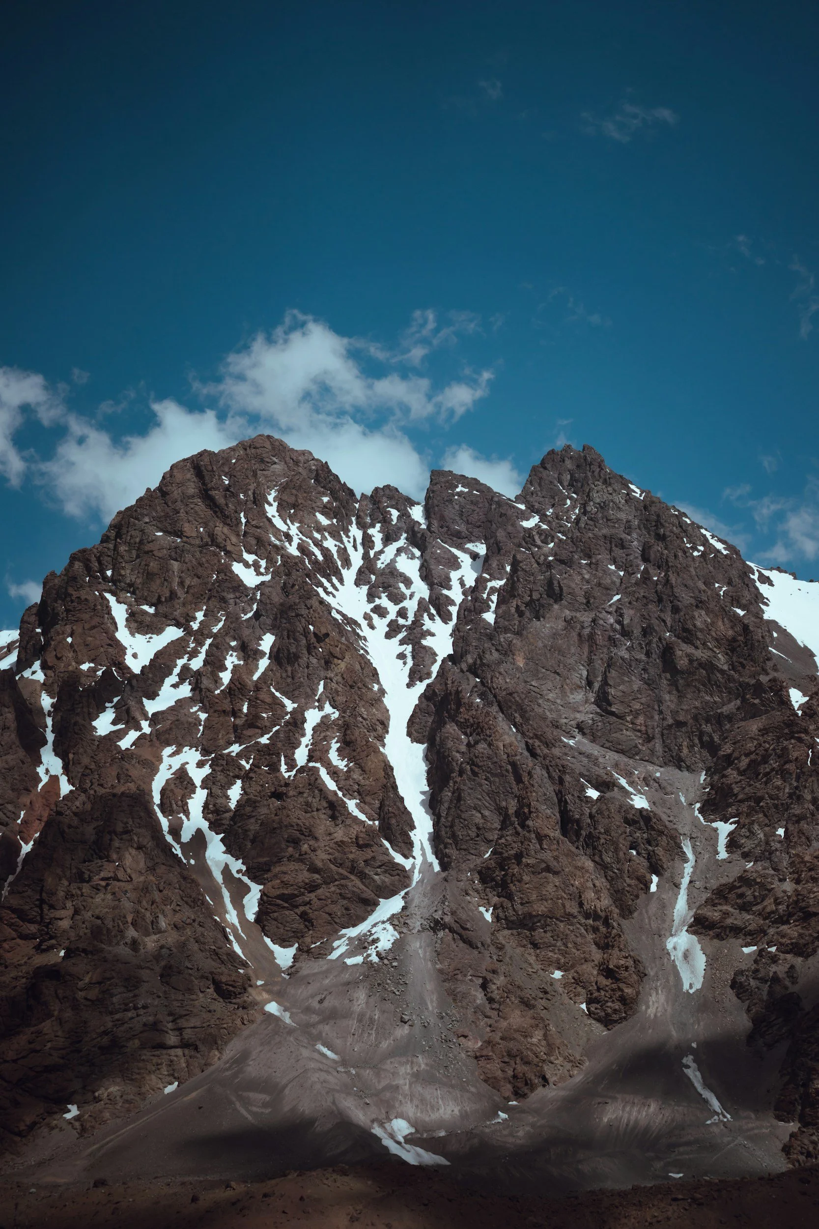 Snow-covered rocky mountain peaks under a partly cloudy blue sky.