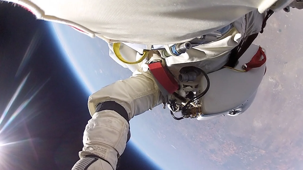 A person in a space suit floating in space, attached to a spacecraft with Earth visible below and the sun shining brightly in the background.