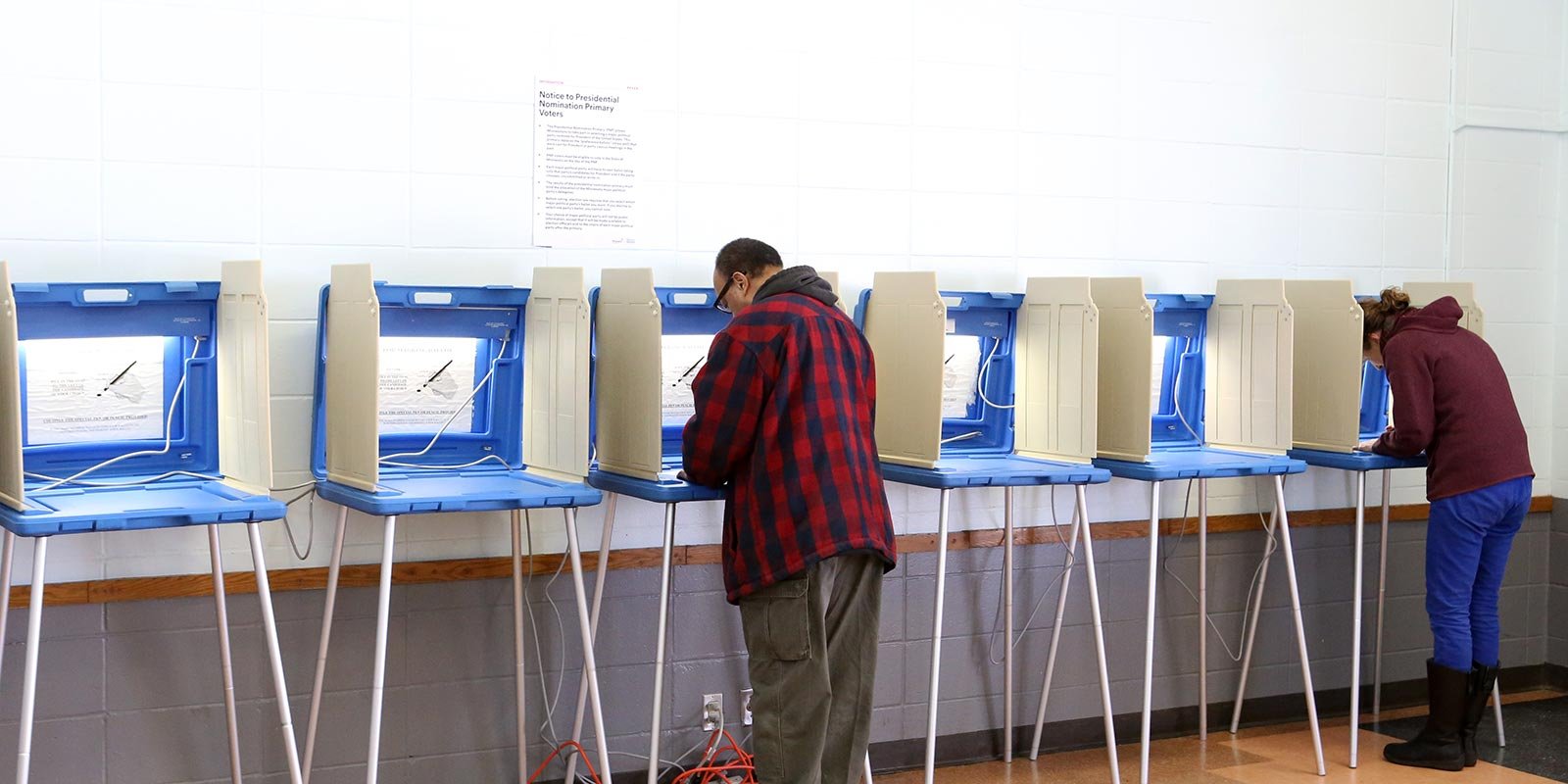 Two people voting at polling booths in an election polling station.