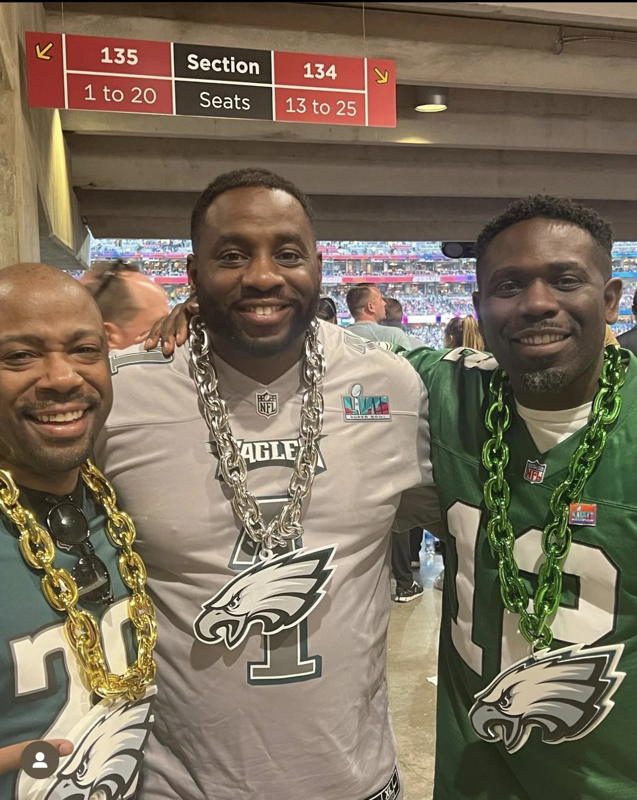 Three men celebrating at a sports stadium, wearing Philadelphia Eagles jerseys with large chains and eagle logos around their necks.