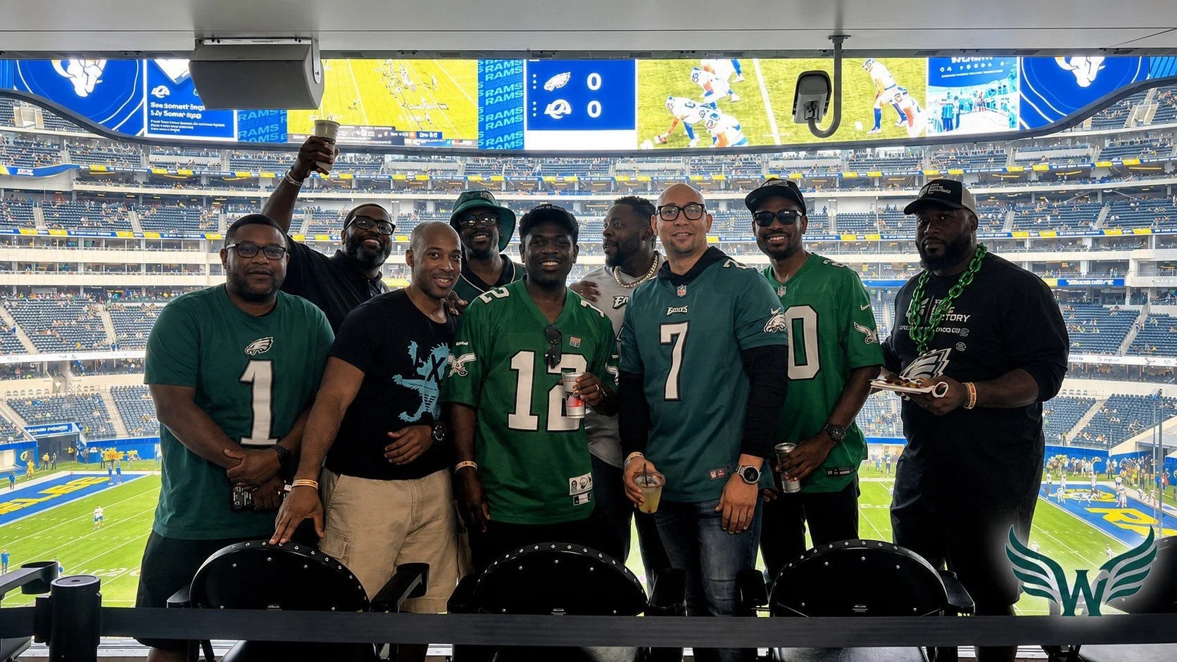 Group of football fans in Philadelphia Eagles jerseys at a stadium, celebrating and enjoying drinks before a game.