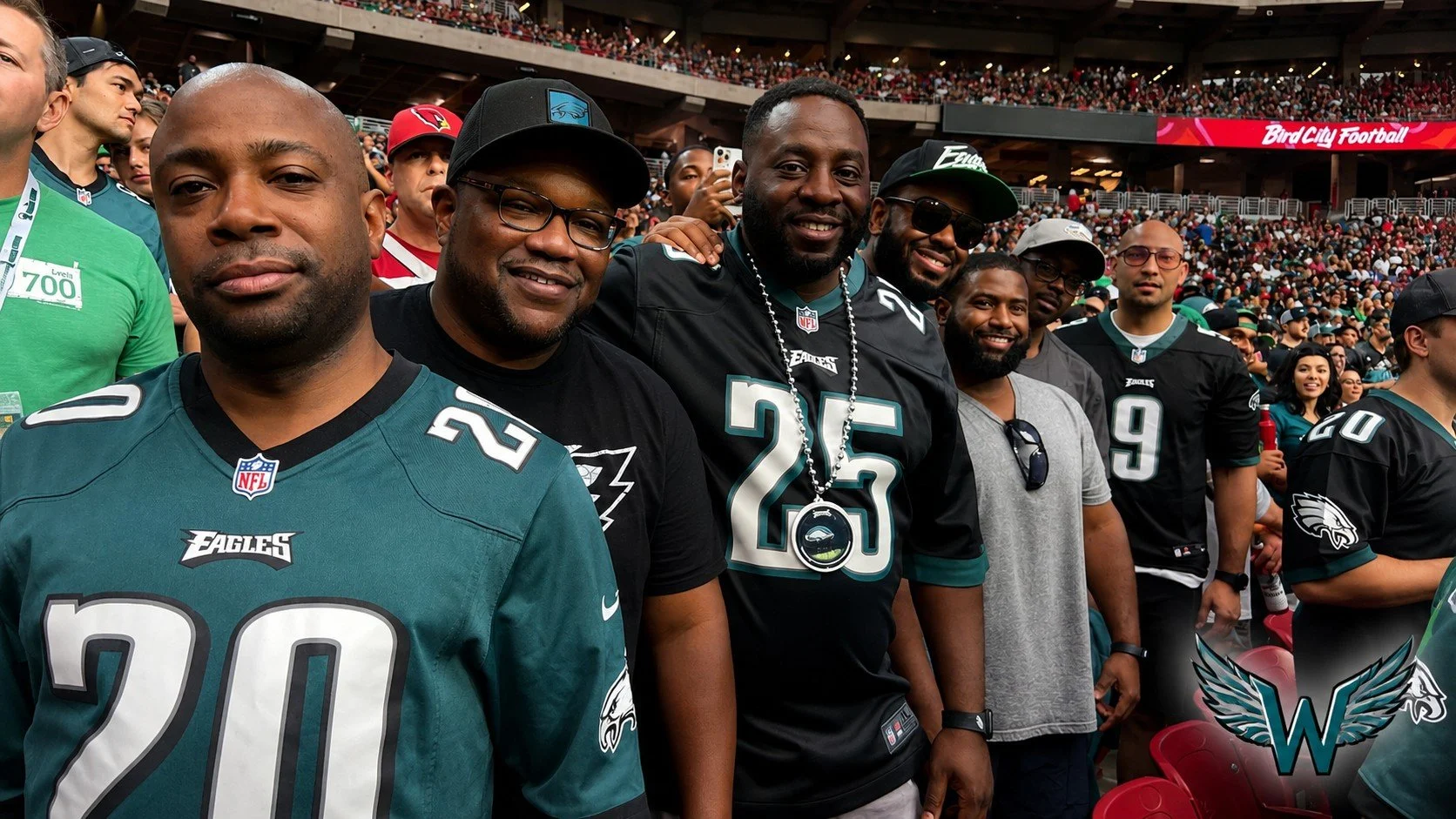 Group of men in football jerseys attending a game at a stadium, with a crowd in the background and a sign that reads 'Bird City Football'.