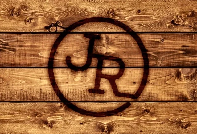 Wooden wall with a black, circular logo containing the letters JR in the center.