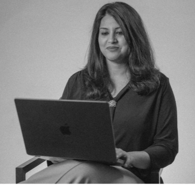 A woman sitting and looking at a laptop in a gray-scale image.