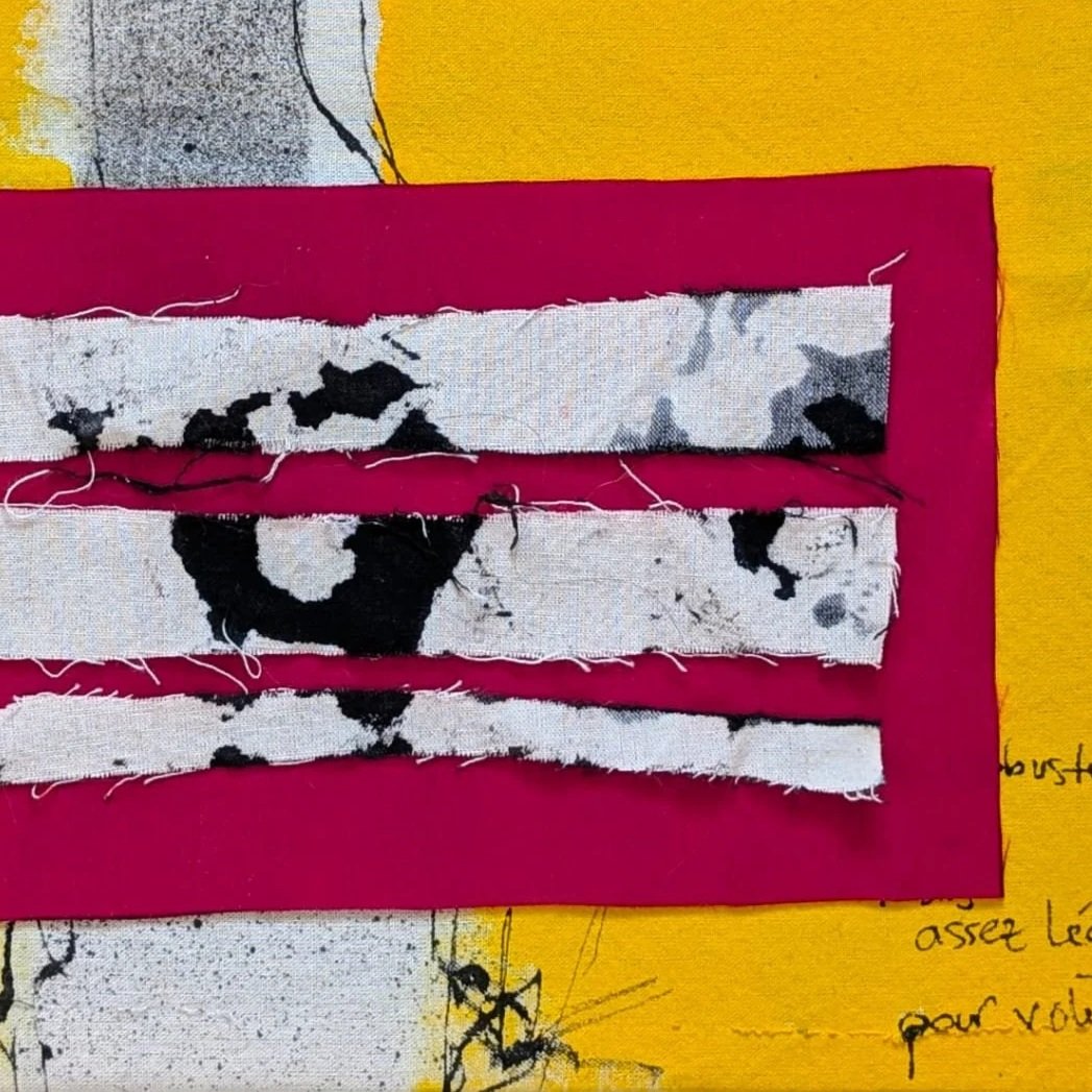Close-up of a very expressive and happy piece of art that shows torn fabric strips on a pink background, placed on a yellow sheet with handwritten notes.