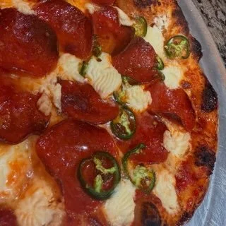 Close-up of a pizza topped with pepperoni, sliced jalapeños, and melted cheese.