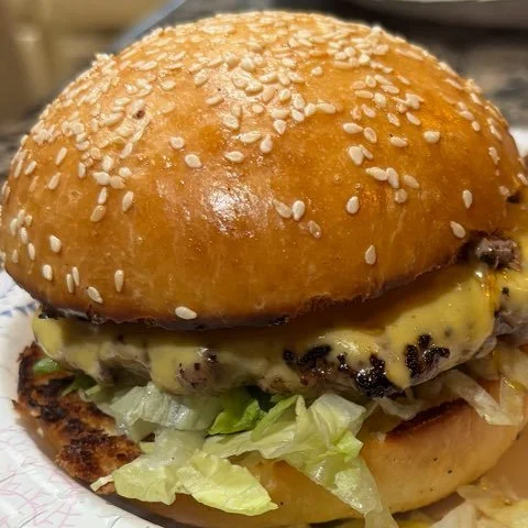 Cheeseburger with lettuce on a sesame seed bun.