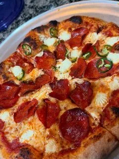 Sliced pepperoni pizza with green peppers on a white plate