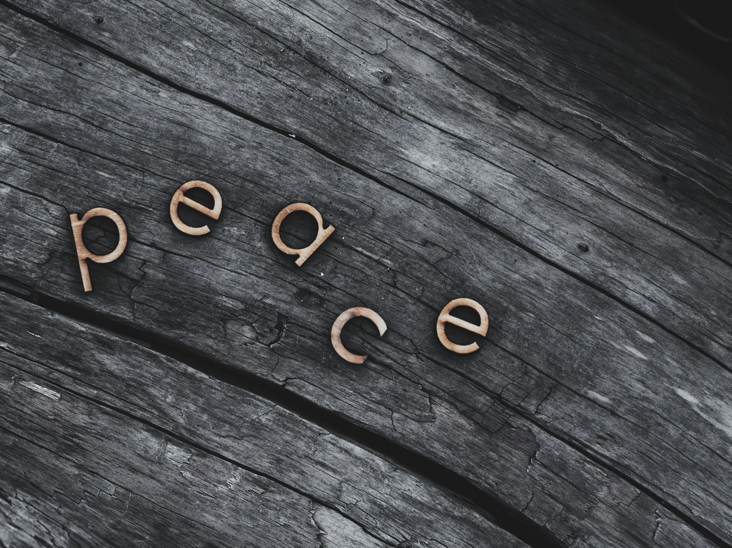 Wooden letters spelling 'peace' on a weathered wooden surface.
