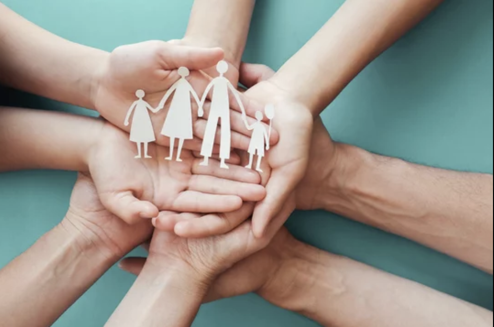 Multiple hands forming a circle around paper cutouts of a family of four, symbolizing unity and support.