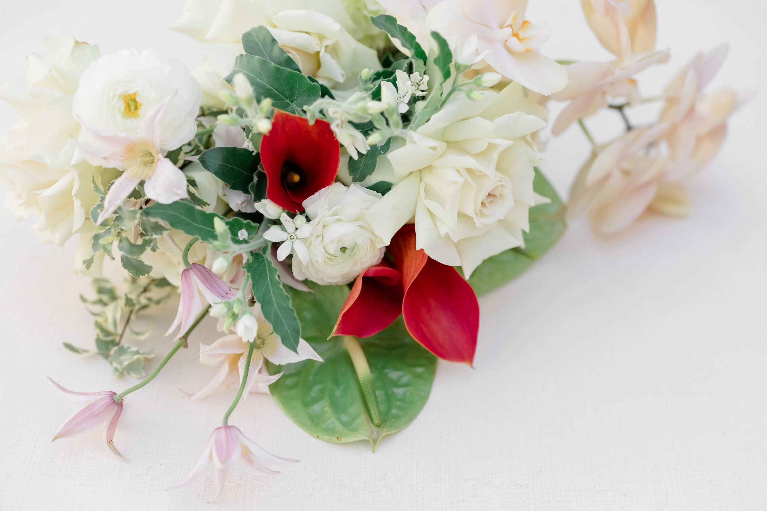 A close up of a beautiful bridal bouquet of creams, whites and with pops of red.