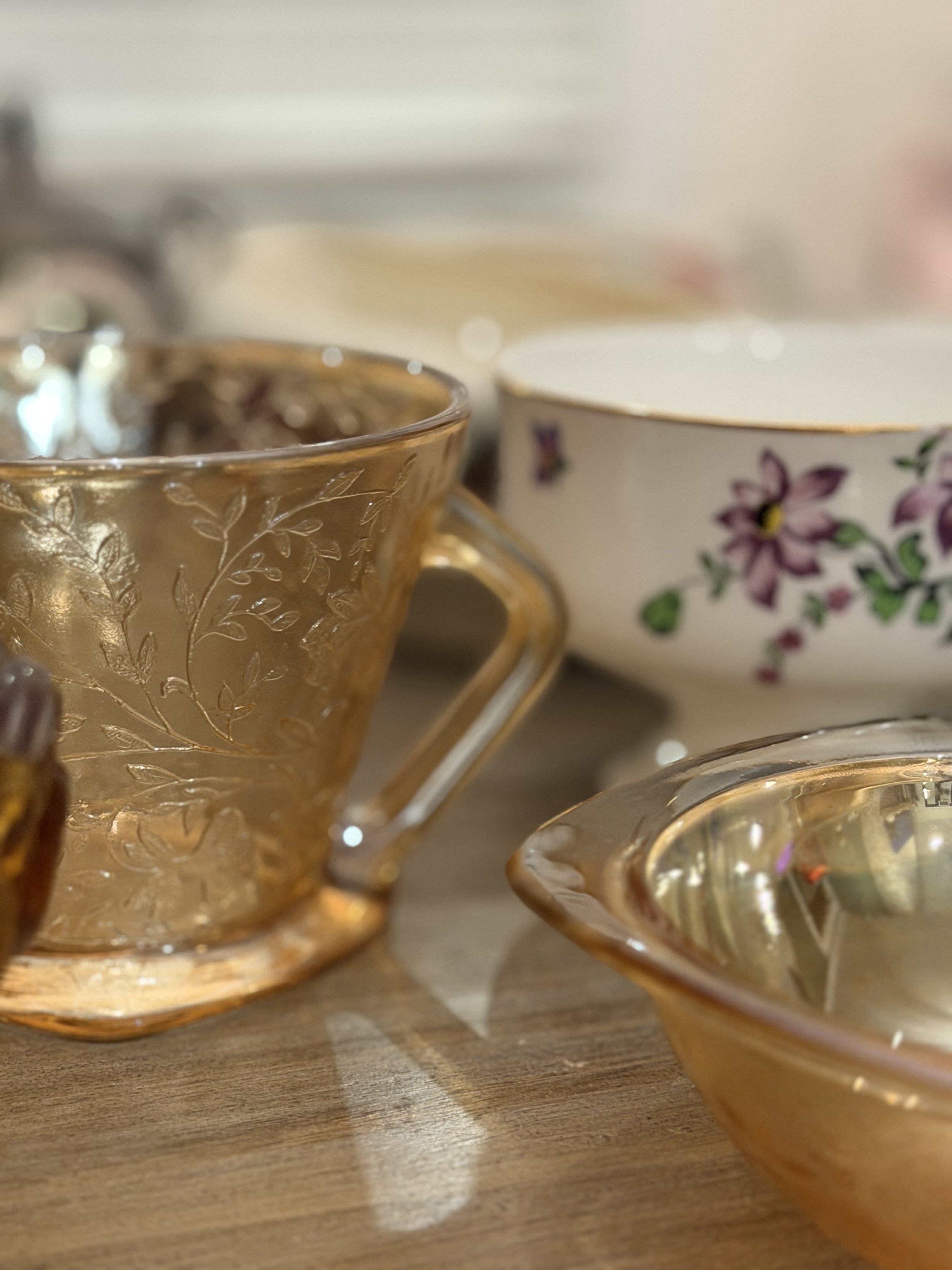 Close-up of various glassware cups and bowls on a wooden table, with a blurred background.