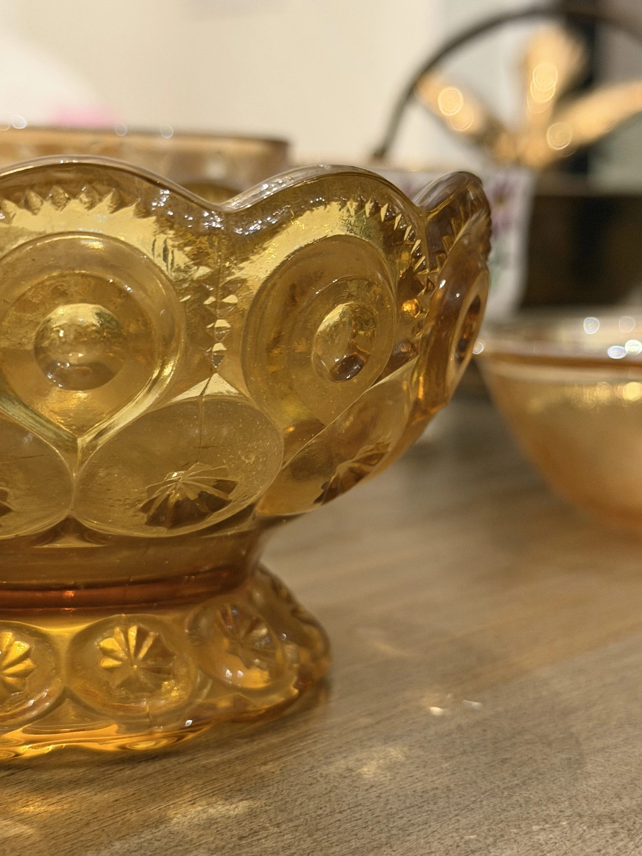 Close-up of a vintage, amber-colored glass bowl with a decorative pattern on a wooden table.