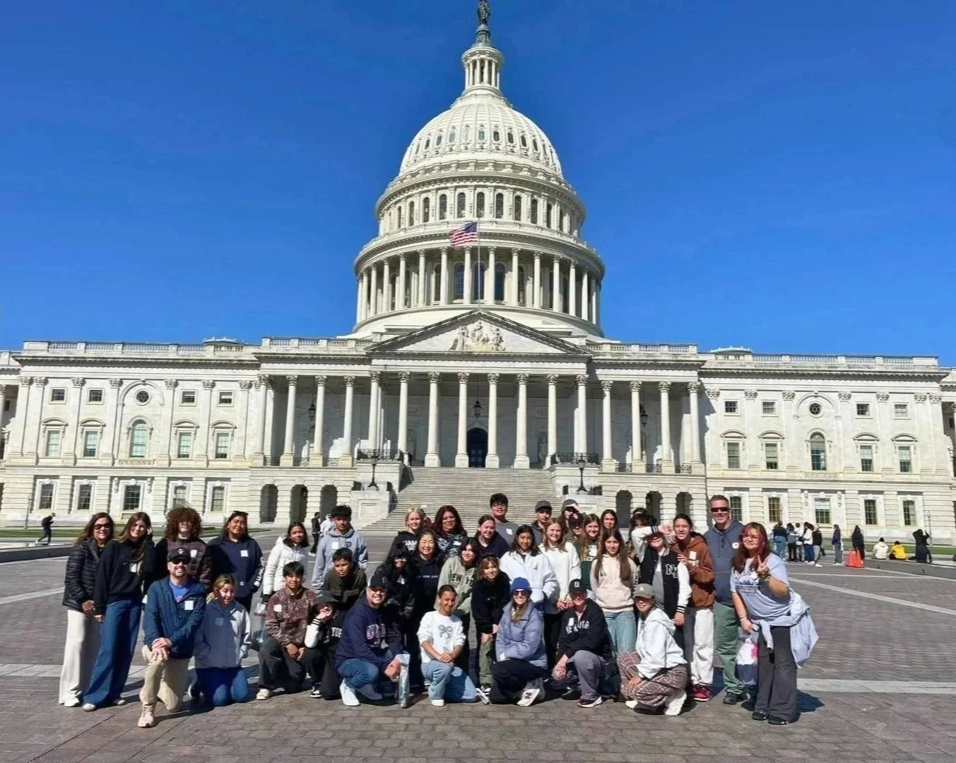 Group of middle school students posing in front of the U.S. Capitol building during daytime with clear blue sky on a Santa Ynez Elementary School field trip.