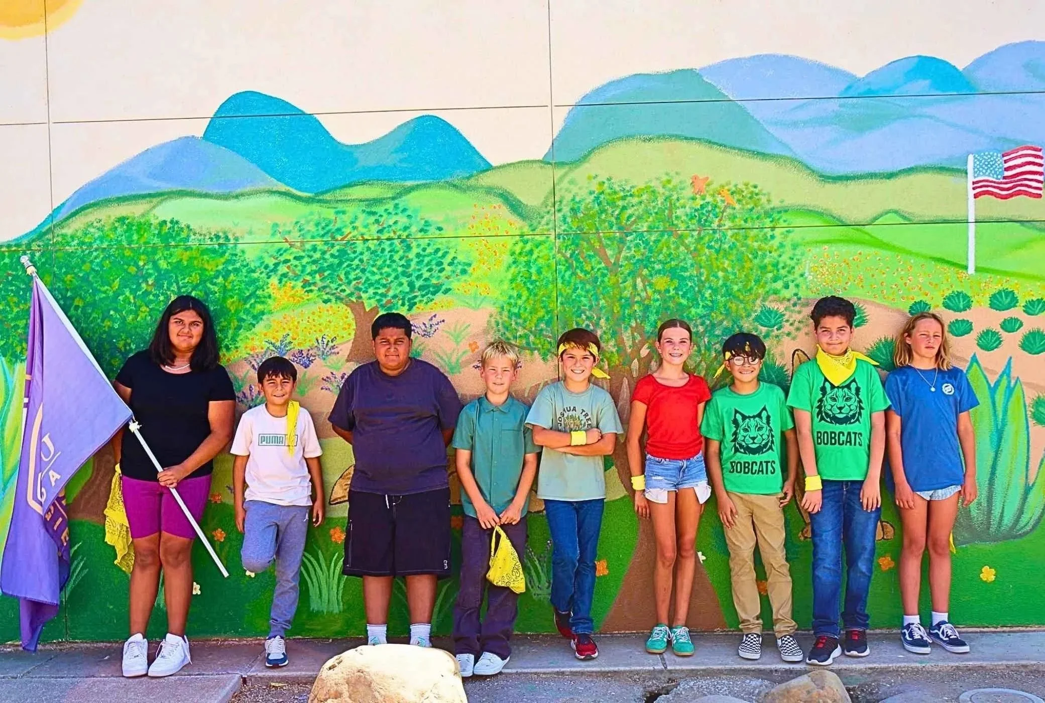 Group of students on the Santa Ynez Elementary School campus standing in front of a colorful mural of mountains, trees, and a Patriot flag.