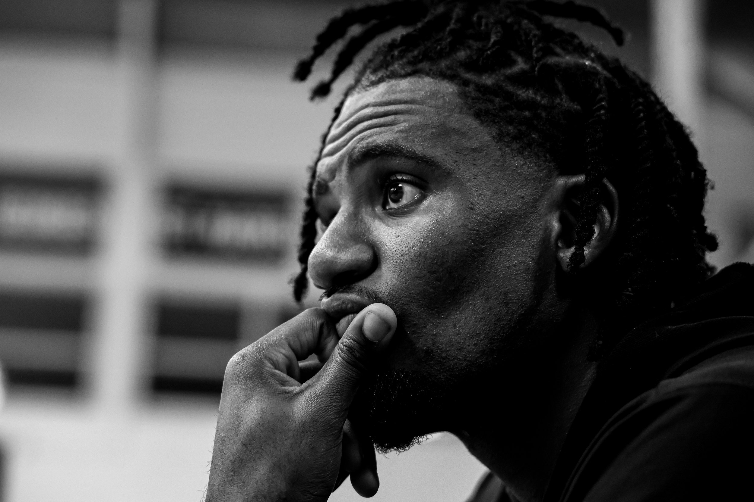 Black and white close-up of a young man's face, with his hand resting near his chin, looking contemplative.