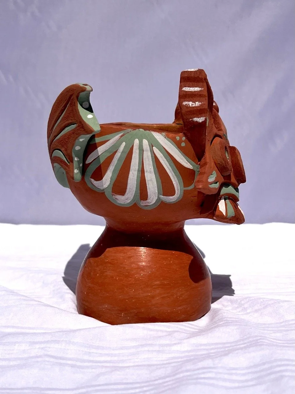 Colorful ceramic bird figurine with floral designs on a white surface with a plain background.