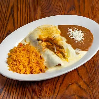 Plate of Mexican food with rice, enchiladas topped with sauce and cheese, served with refried beans garnished with cheese.