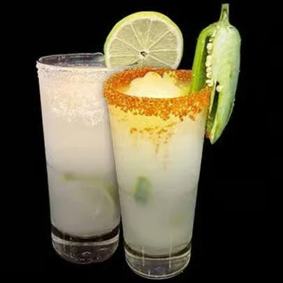 Two glasses of limeade with lime slices and cucumber slices, one garnished with chili powder around the rim and a slice of cucumber on the rim, set against a black background.