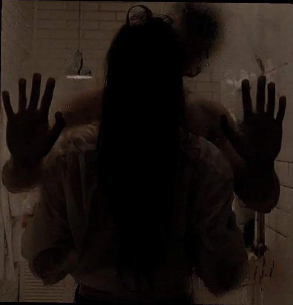 A figure in silhouette behind fogged glass