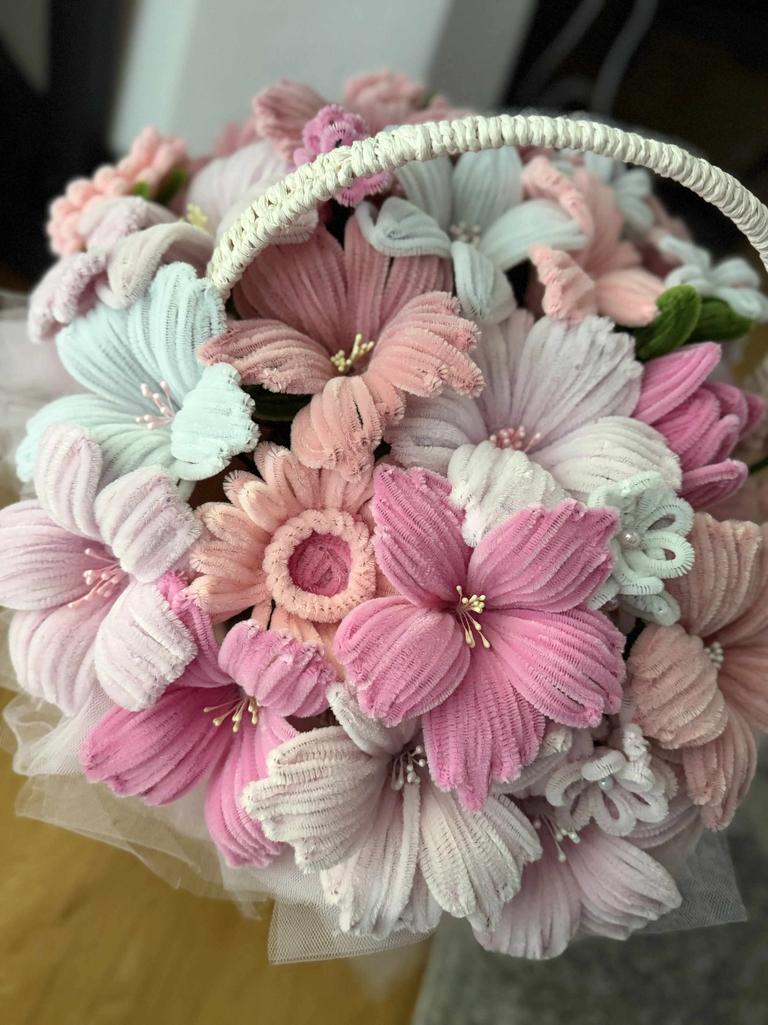 Bouquet of flowers made from pink, white, and light blue fabric with velvet, corduroy, and lace textures, arranged in a decorative manner.