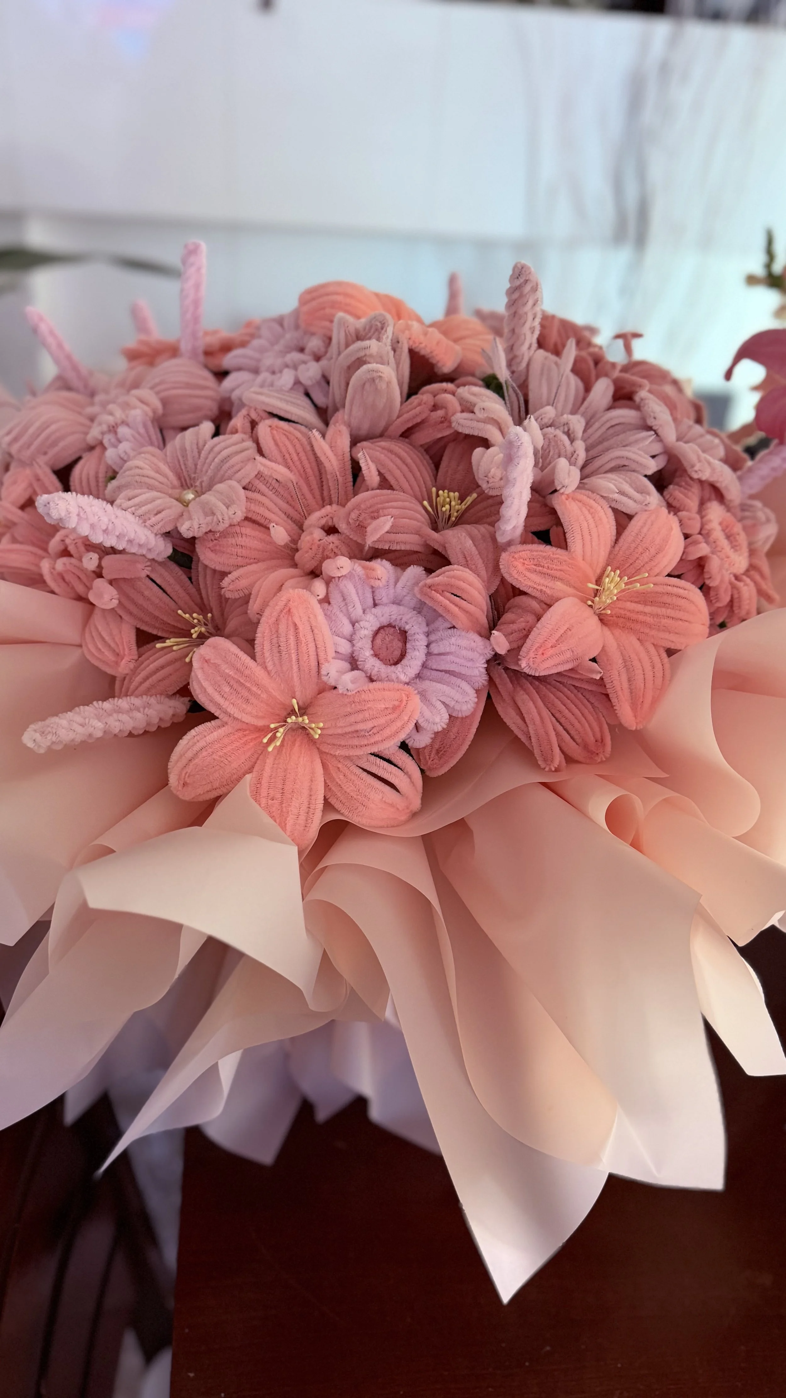 Bouquet of pink flowers wrapped in pink paper with large pink paper wrapping at the bottom.